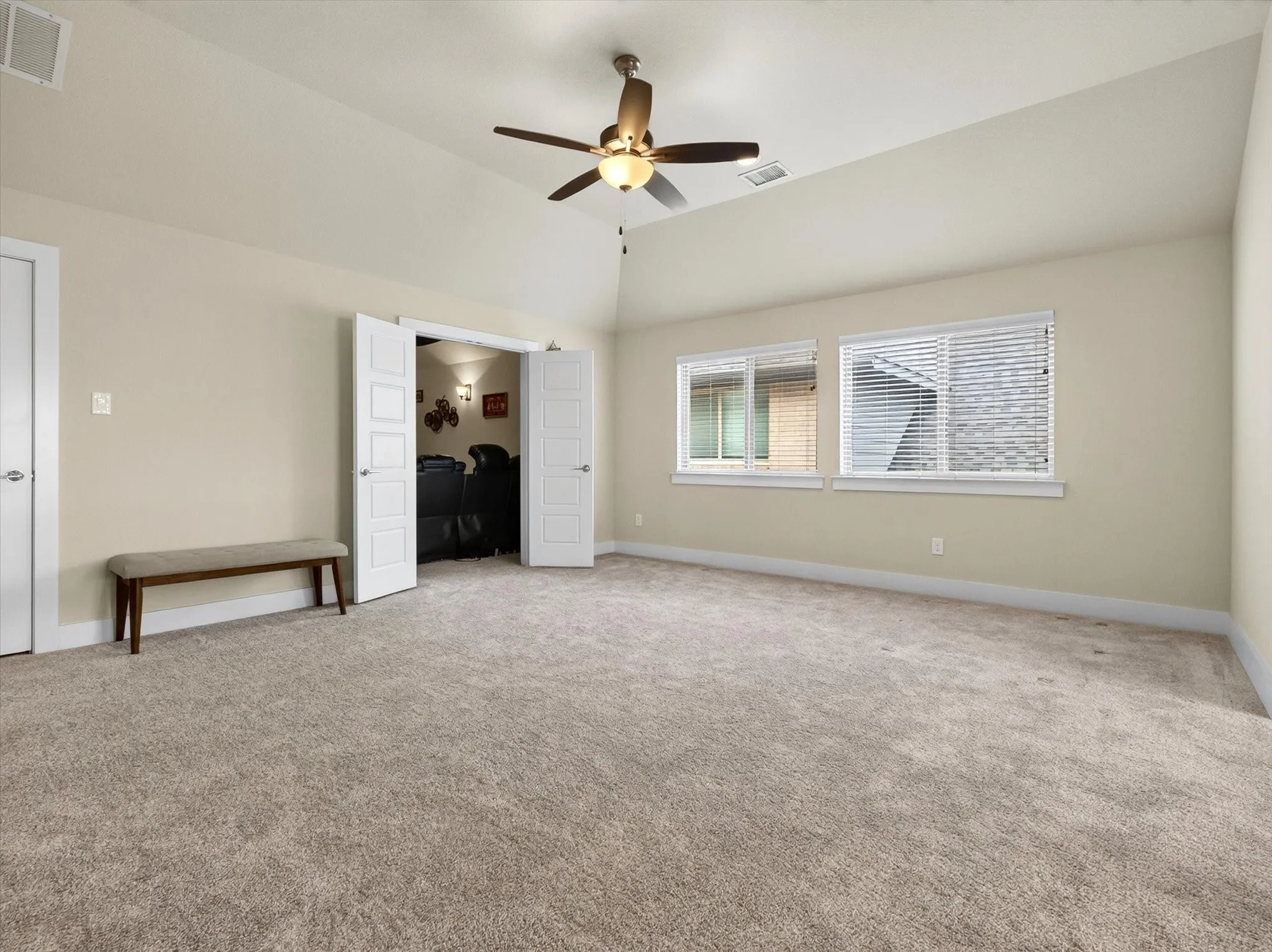 Spacious room featuring vaulted ceilings, light-toned walls, and neutral carpeting