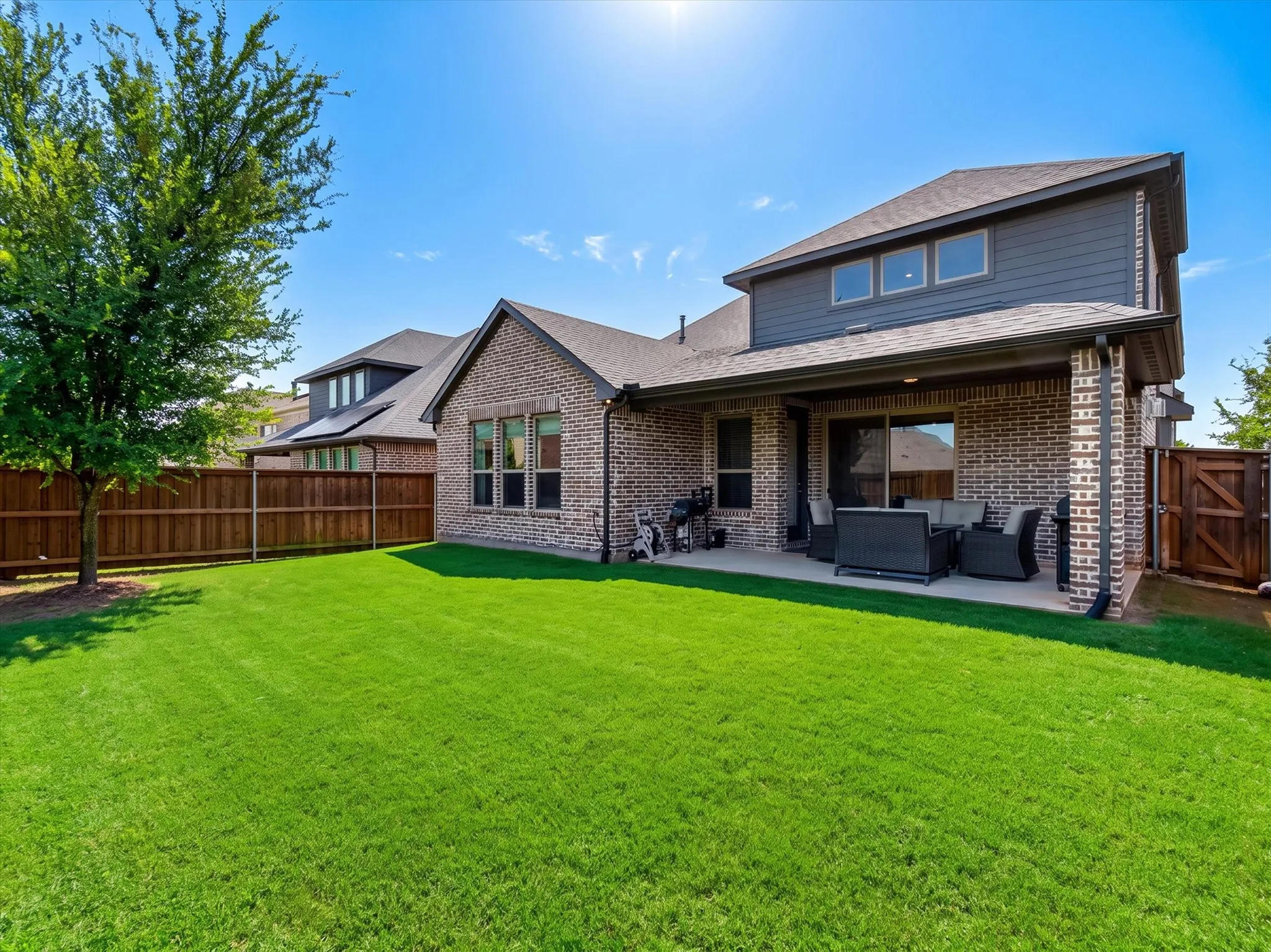 Expansive backyard featuring a lush lawn, privacy fencing, and a mature tree