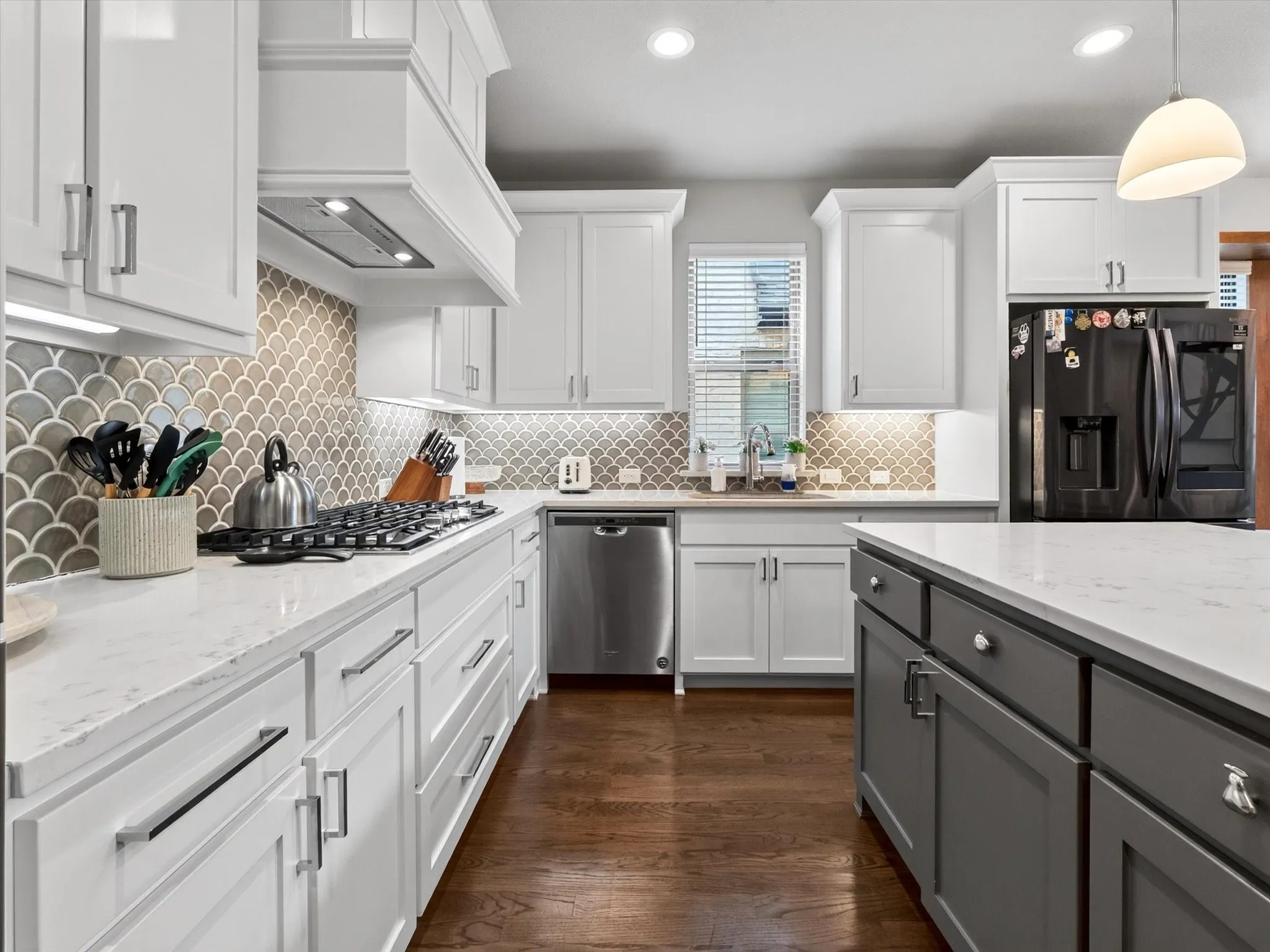 Contemporary kitchen featuring white shaker cabinetry, stainless steel appliances, and a scalloped tile backsplash