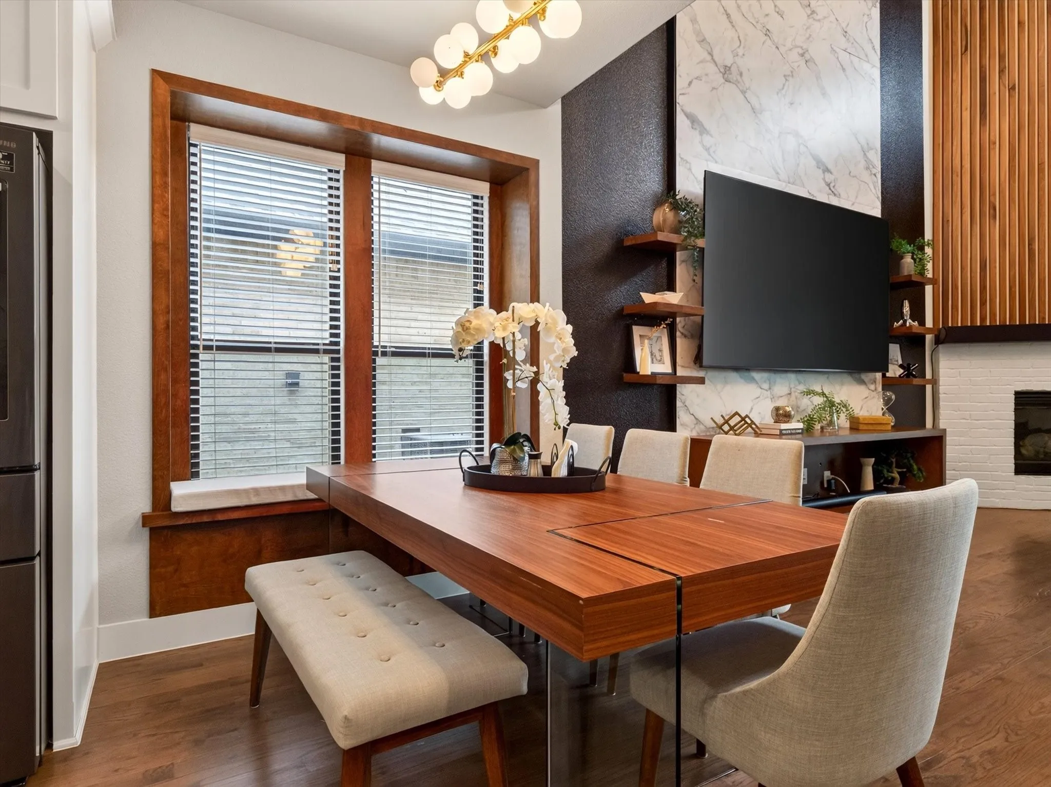 Open dining space featuring a large wood-finish table, a built-in window seat, and wood-finish flooring