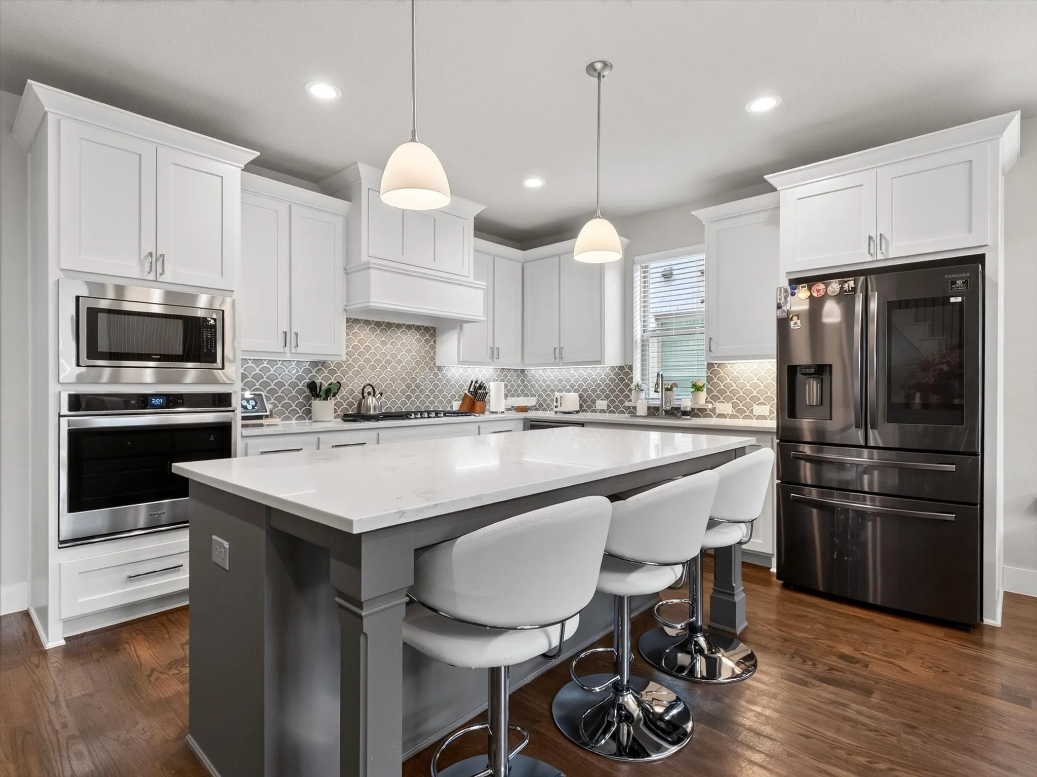Kitchen featuring a central island with a light-toned countertop, white cabinetry with crown molding, stainless steel appliances, a decorative tile backsplash, and wood-finish flooring