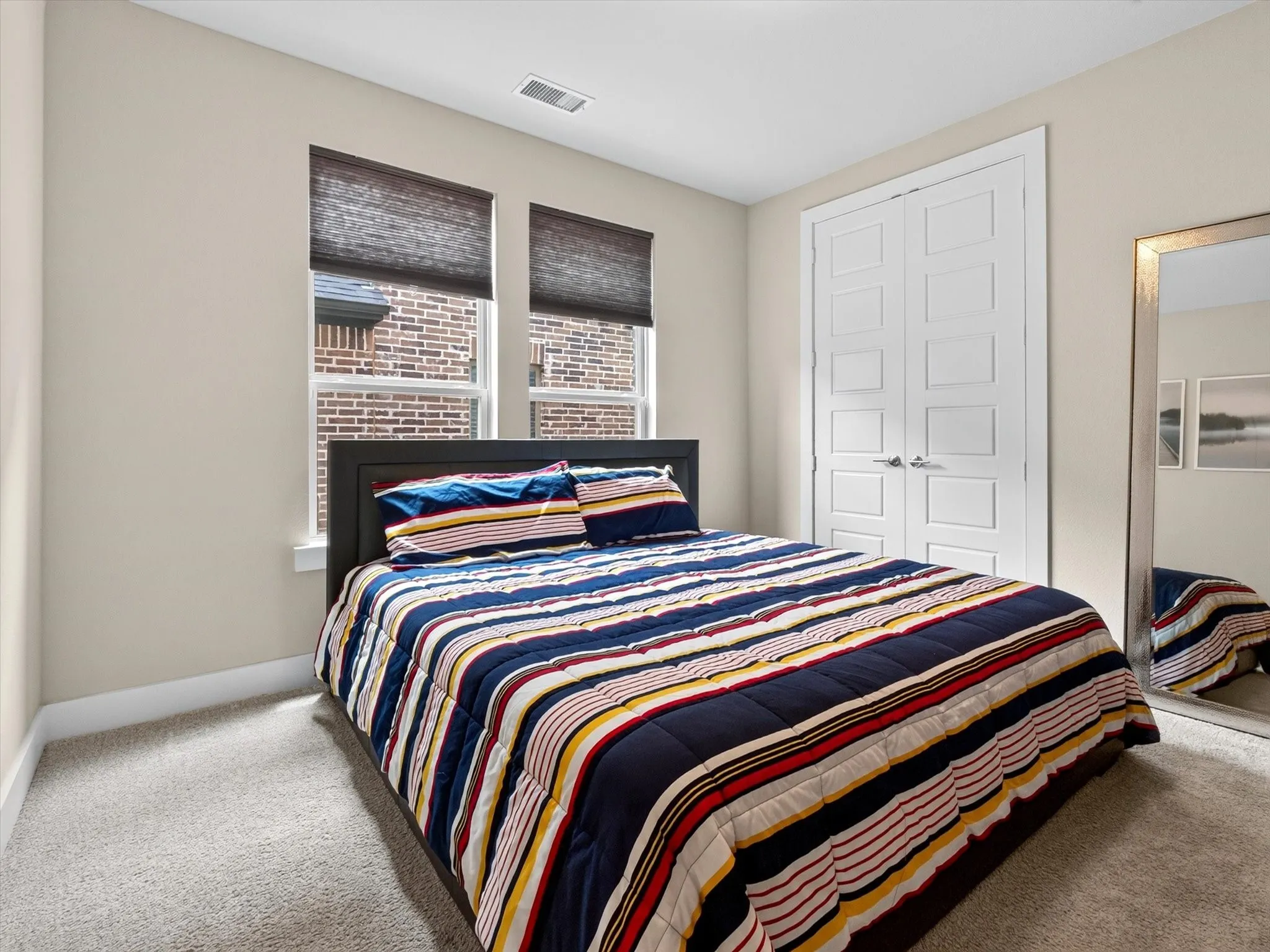 Carpeted room featuring two windows with blinds, a built-in closet with double panel doors, and neutral-toned walls