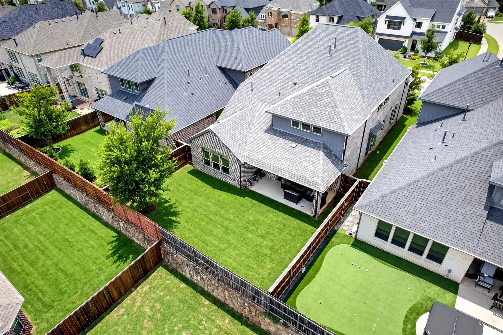 Spacious backyard featuring a large paved patio, covered outdoor living area, and extensive green lawn