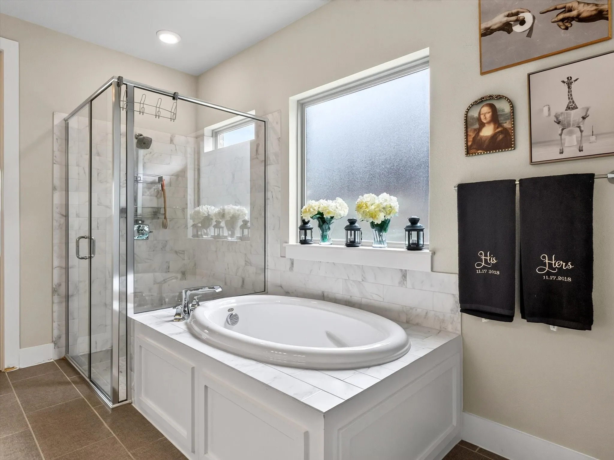 Spacious bathroom featuring a built-in soaking tub with a tiled surround, a glass-enclosed shower, a frosted window, and large format floor tiles