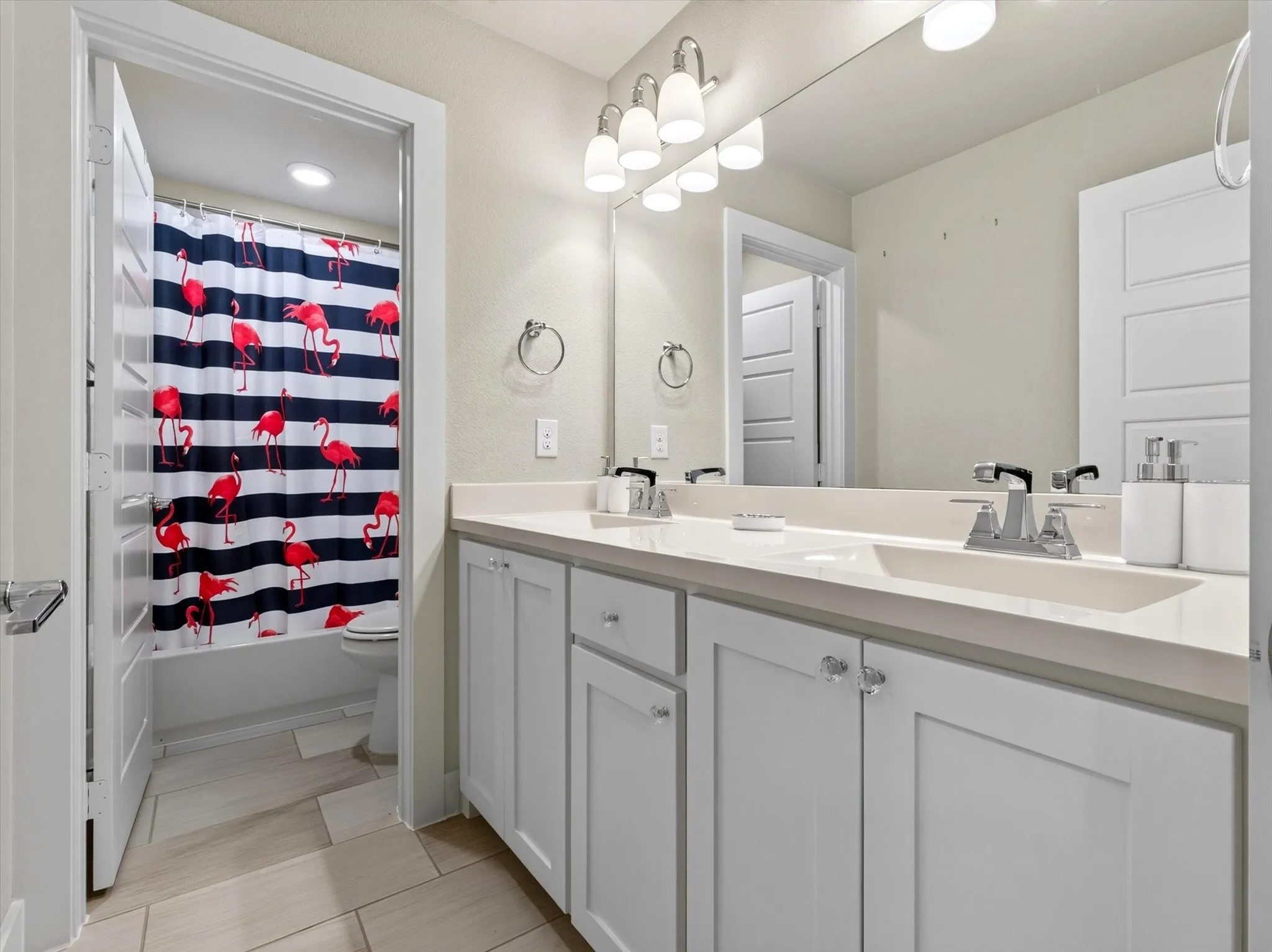 Double vanity with integrated sinks, light-toned countertop, and white shaker-style cabinetry
