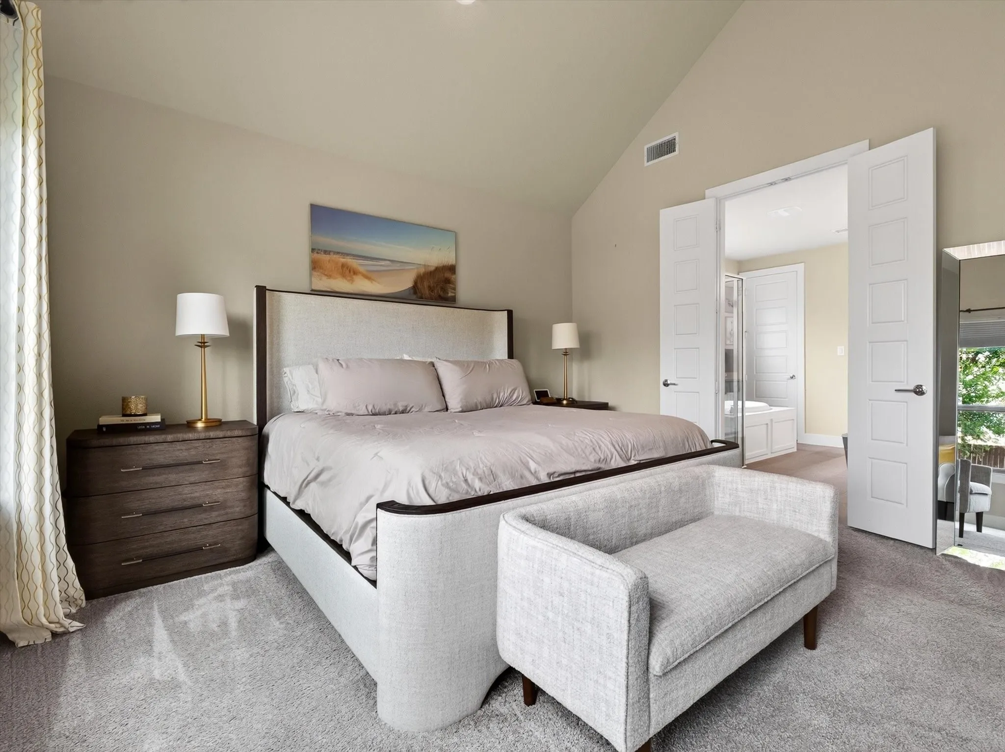 Bedroom featuring a vaulted ceiling, plush carpet flooring, a multi-paneled double door entry, and an architectural vent