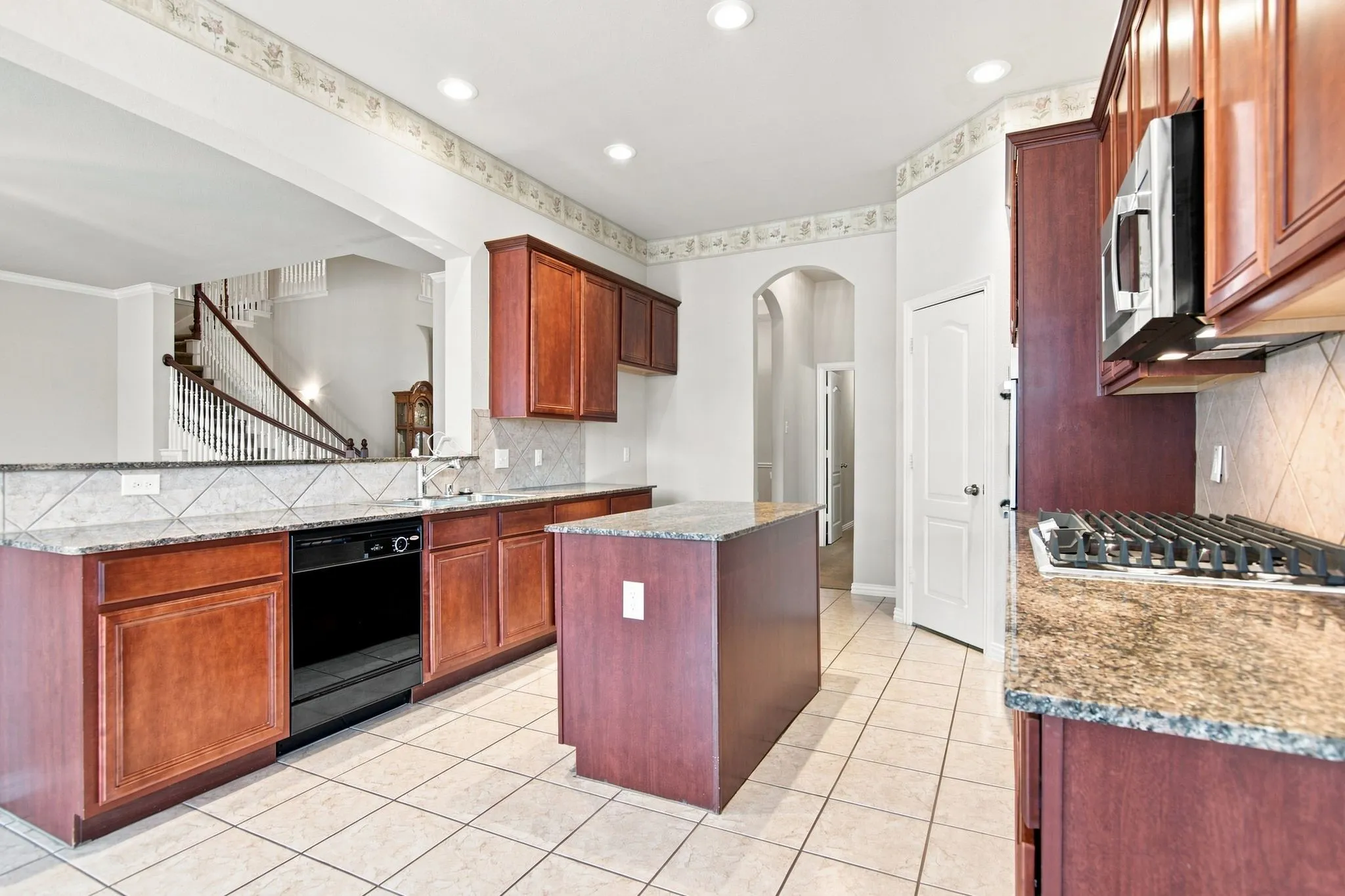 Kitchen featuring wood cabinetry, stone countertops, a tile backsplash, and a central island