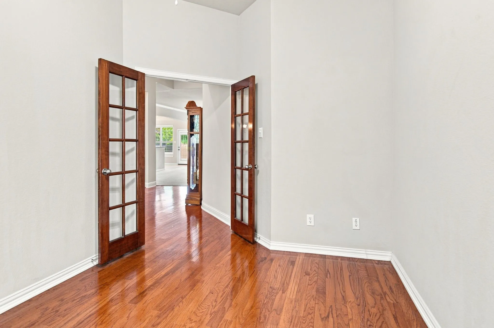 Hardwood flooring throughout, with a light wall color, and wood-paneled double doors