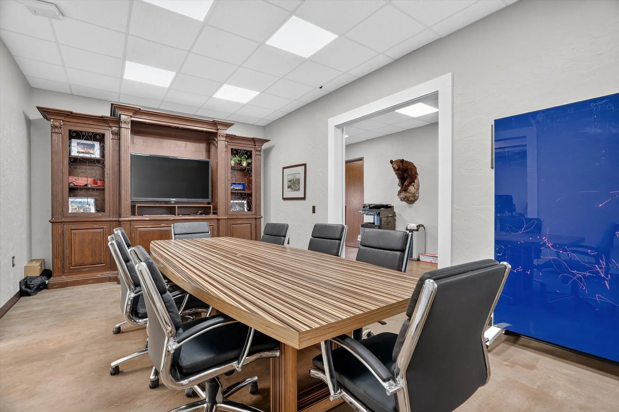 Conference room featuring a wood-finish table, built-in media console, and acoustic ceiling tiles