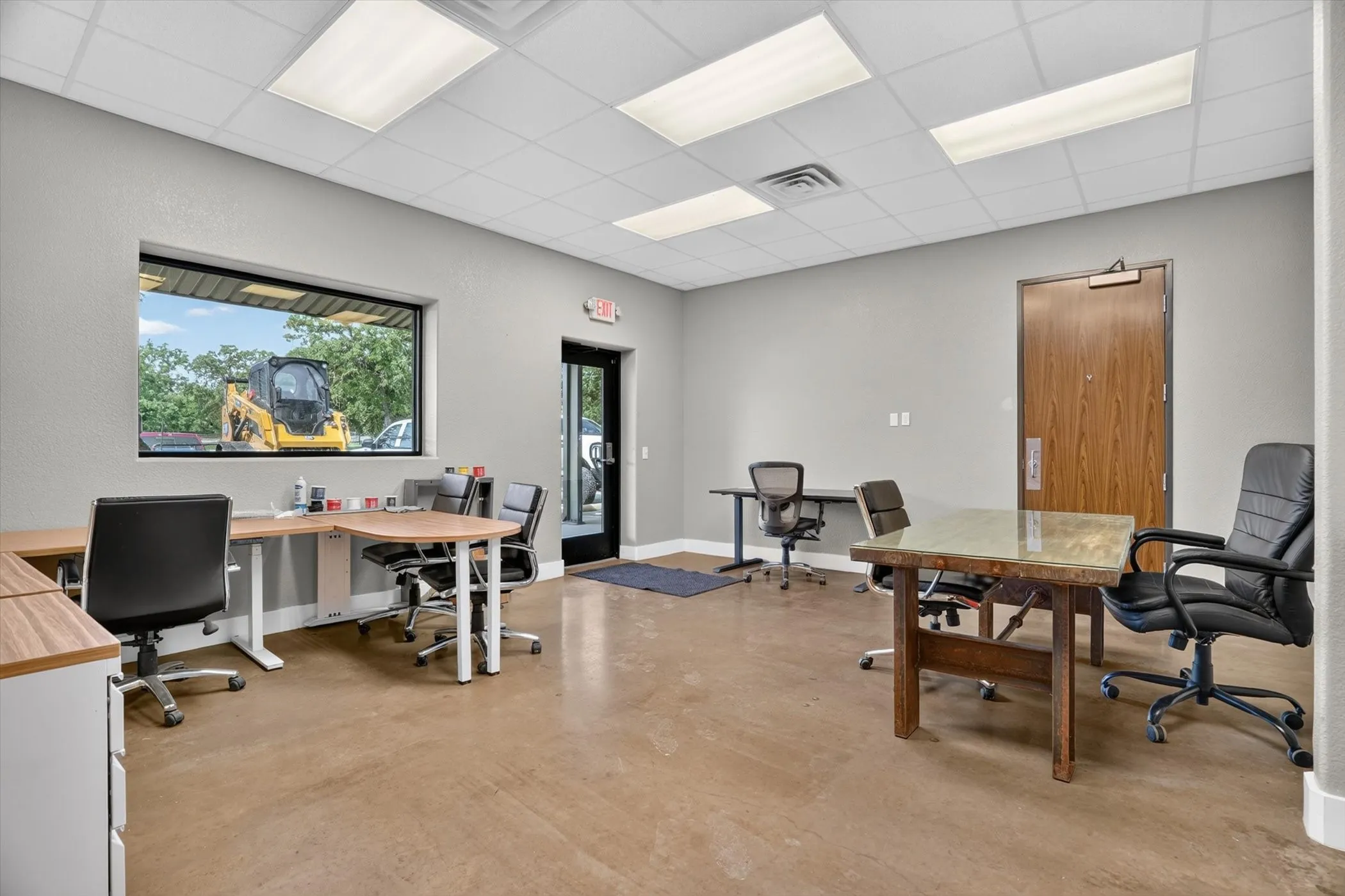 Open office space featuring a large picture window, commercial-grade flooring, recessed ceiling lighting, and a solid core entry door