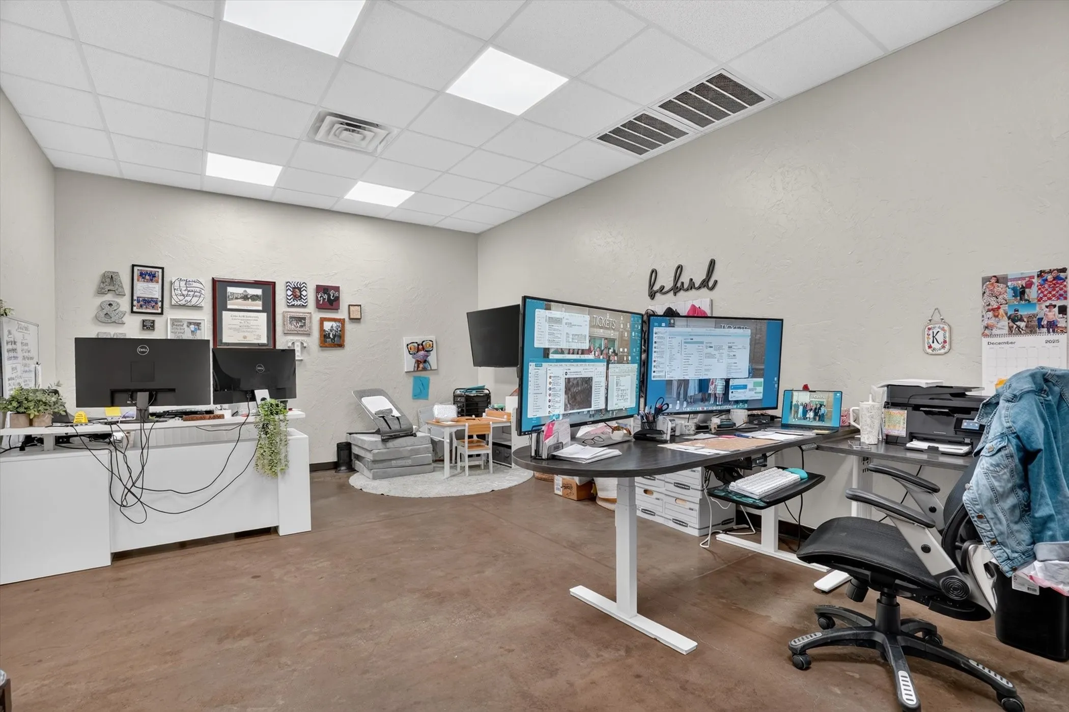Spacious office interior with light-toned walls and a grid ceiling featuring recessed panel lighting