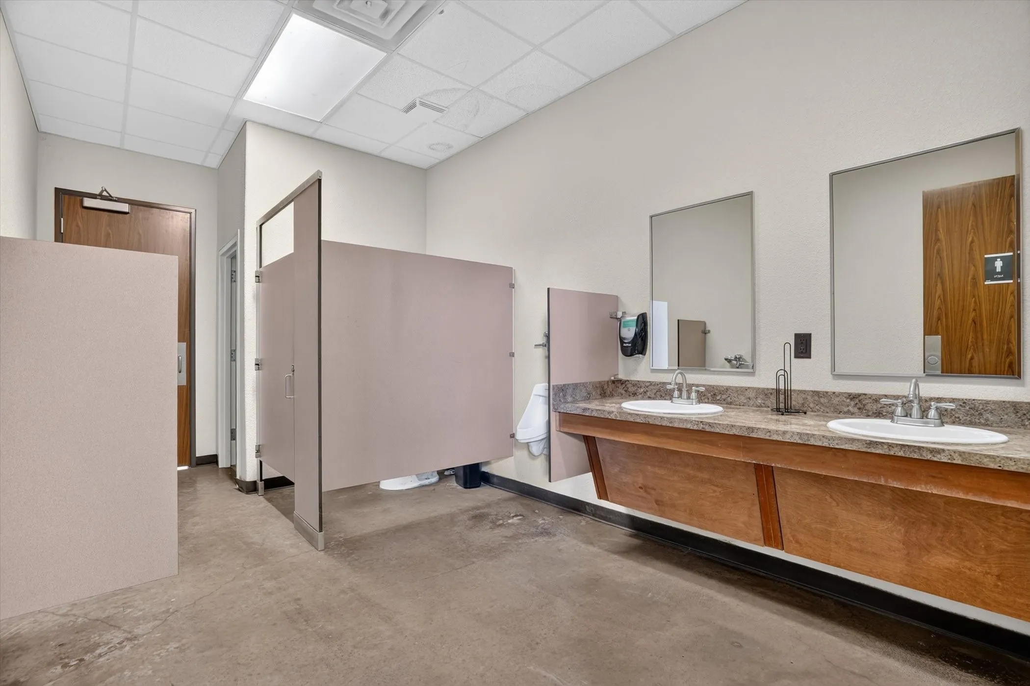 Restroom featuring a dual-sink vanity with a speckled countertop and wood-finish cabinetry