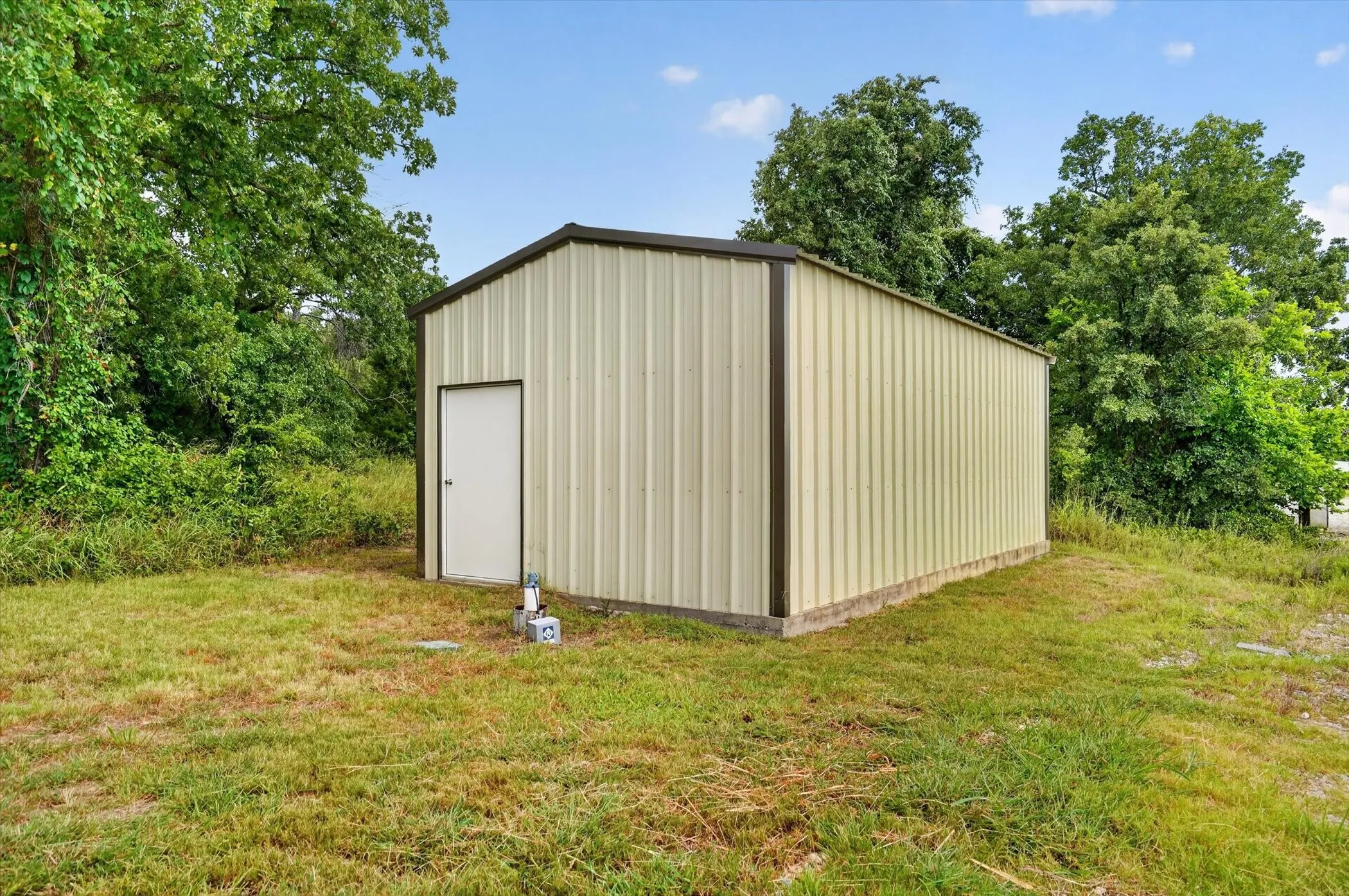 Freestanding metal utility building featuring a single entry door and a pitched roof
