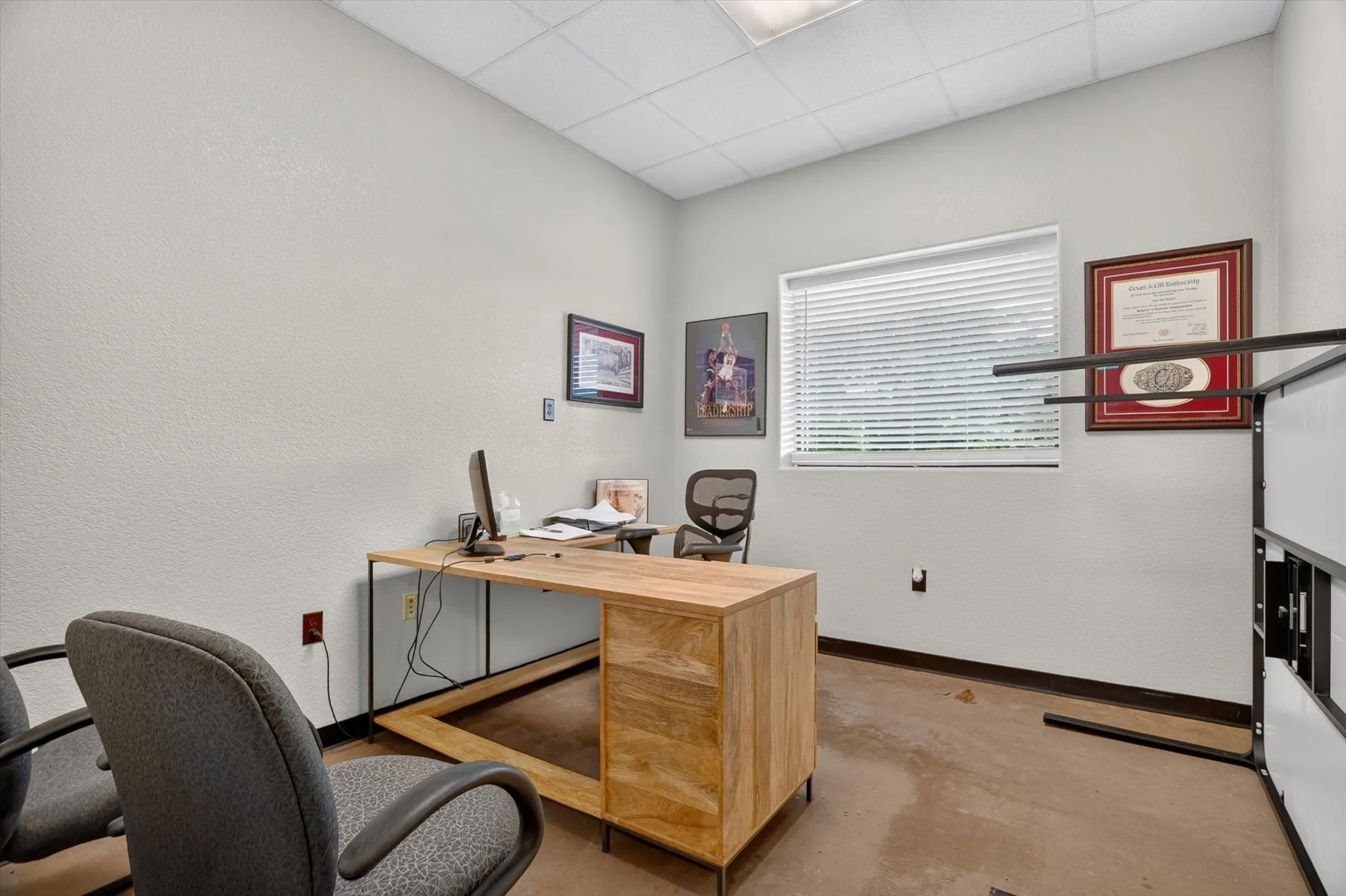 Office space featuring a large window with blinds, light-toned walls, and a dropped ceiling with recessed lighting