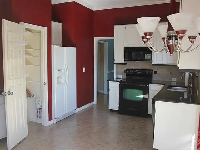 Kitchen featuring white cabinetry, black countertops, a tile backsplash, and a black appliance suite