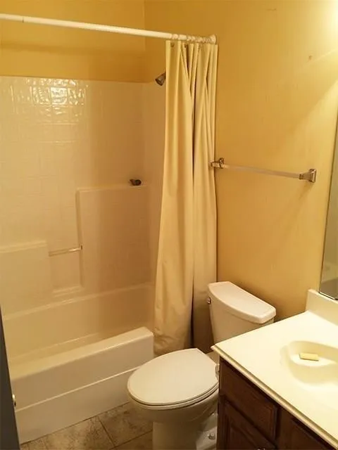 Bathroom featuring a tub/shower combination with white subway tile surround, white toilet, and a vanity with a white countertop and integrated sink
