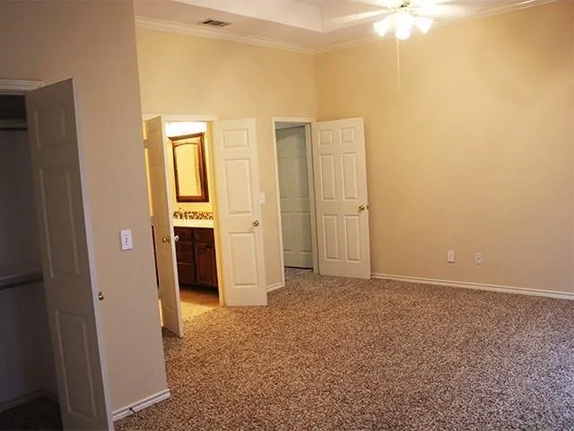 Carpeted room featuring a tray ceiling, crown molding, and a ceiling fan