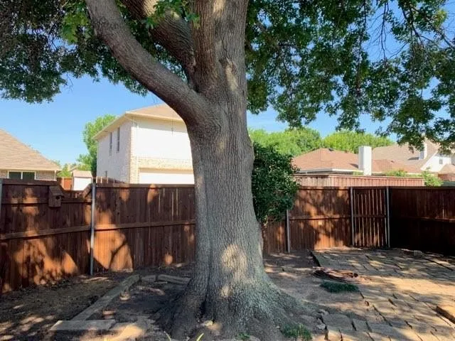 Backyard featuring a mature tree, wood fence, and a gate