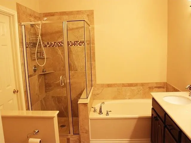 Glass-enclosed shower with full-height tile surround and decorative mosaic band