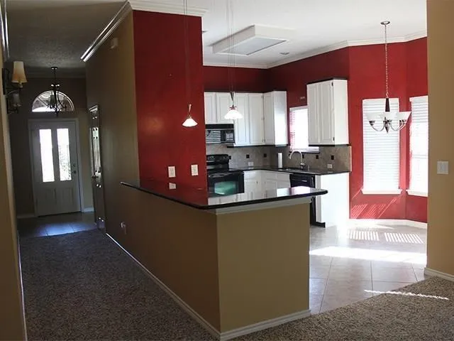 Kitchen featuring white cabinetry, dark countertops, built-in appliances, and a breakfast bar