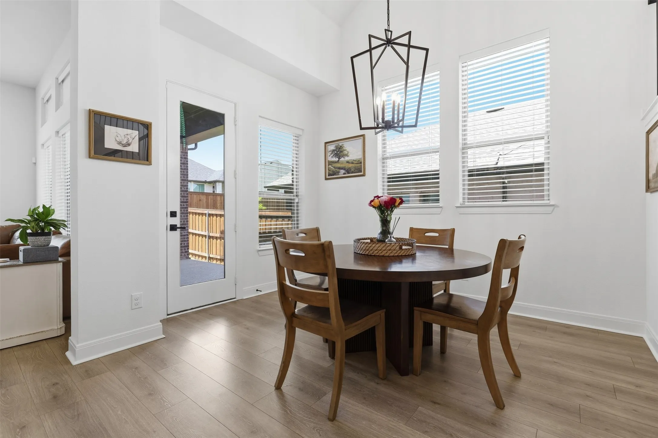 Dining area featuring vaulted ceilings, wood-finish flooring, a modern geometric chandelier, and multiple windows with blinds