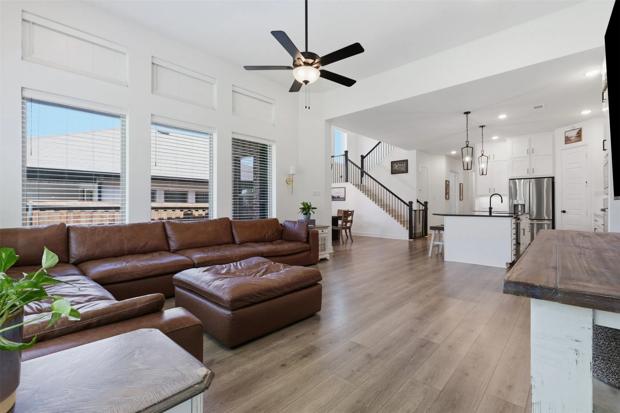 Open-concept living space with wood-finish flooring, a contemporary ceiling fan, and high ceilings