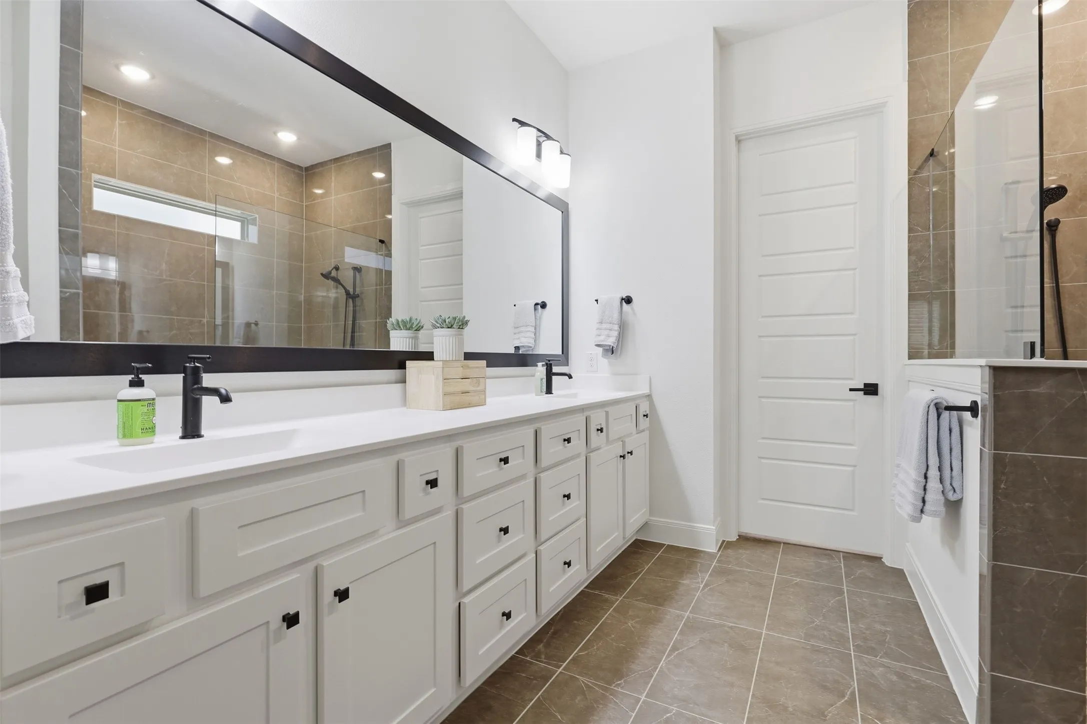 Spacious bathroom featuring an extended white vanity with dual undermount sinks and matte black fixtures