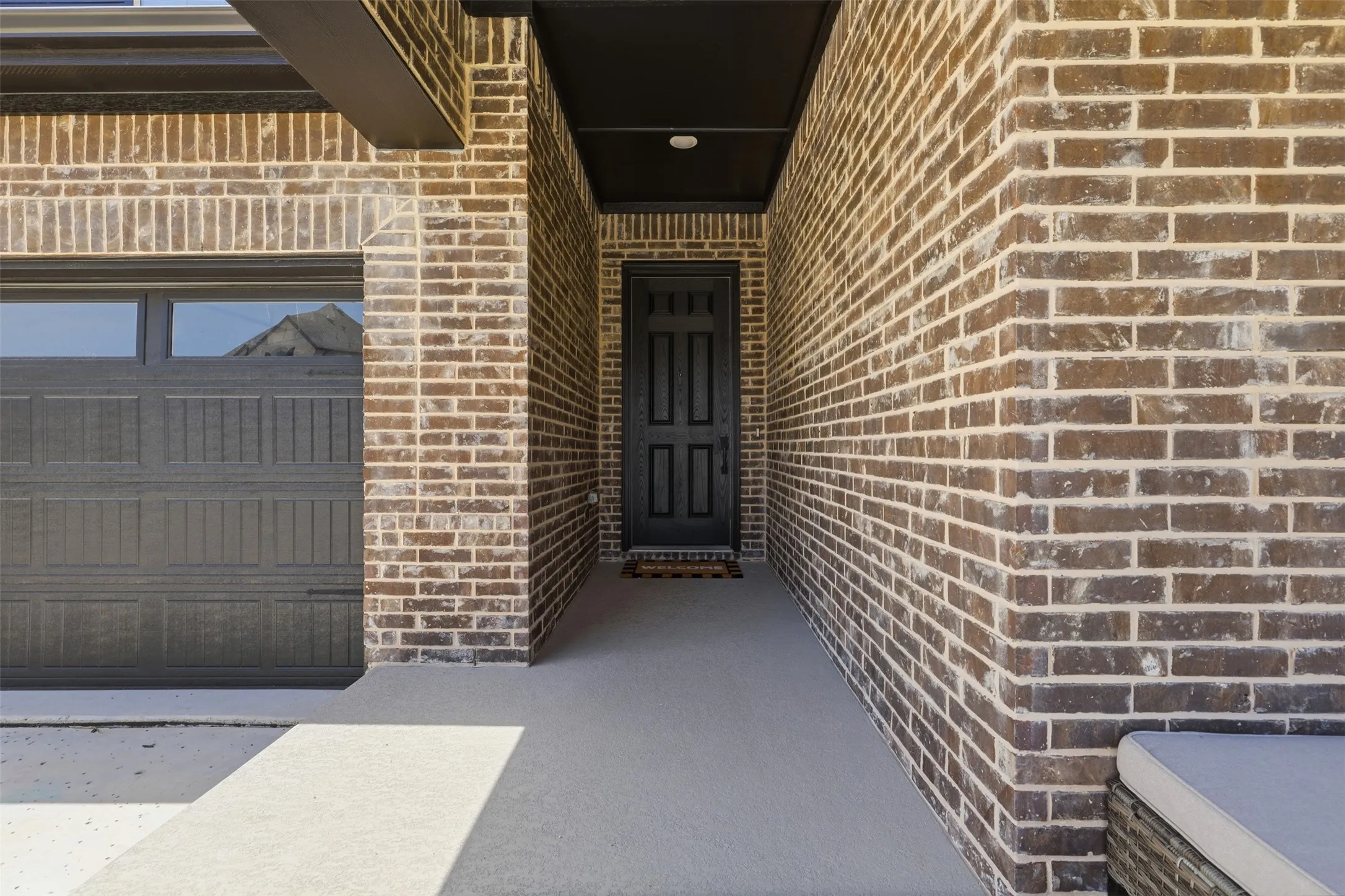 Brick exterior featuring a recessed entry, dark paneled front door, and an attached garage with upper window panels