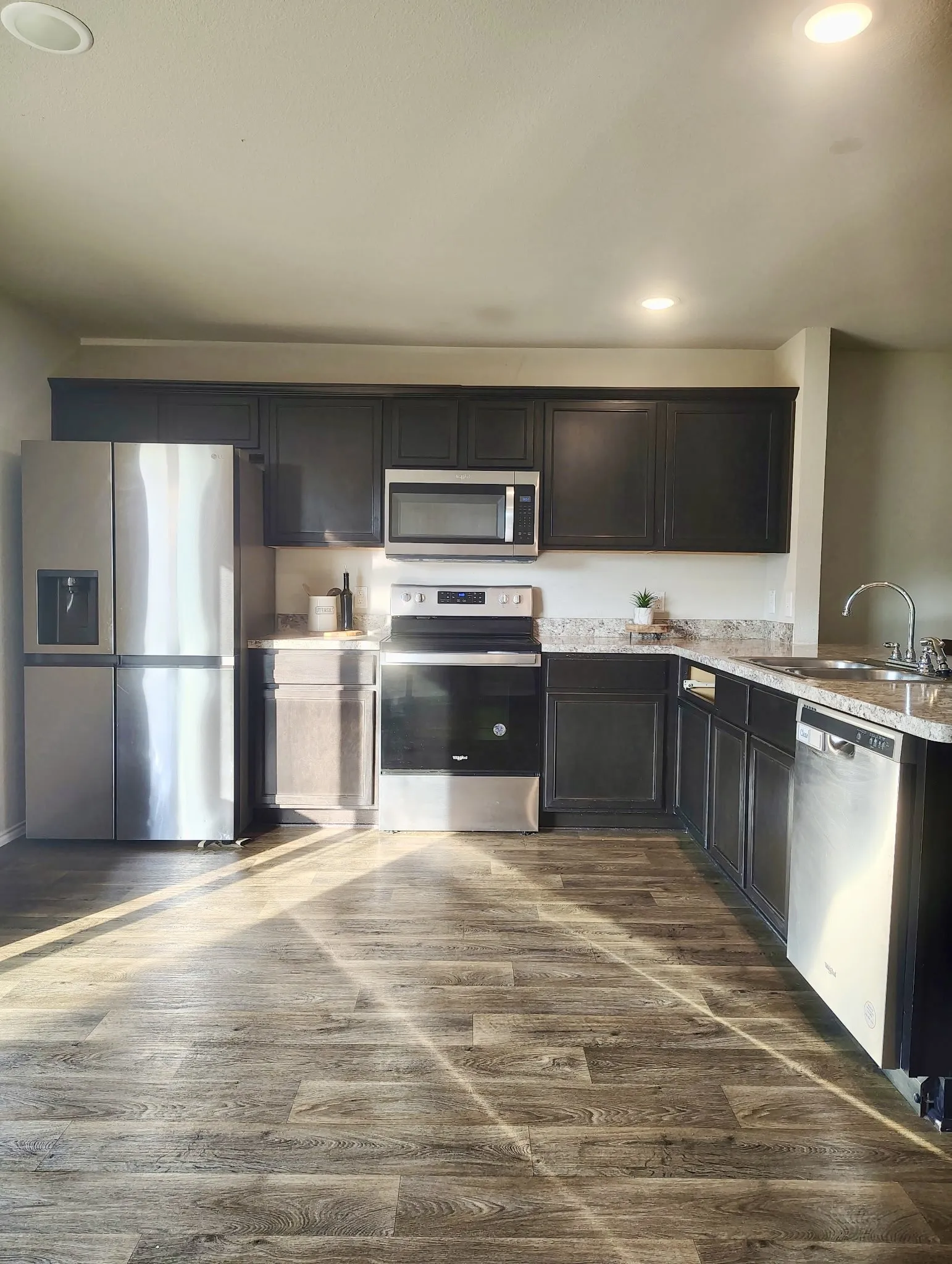 Kitchen featuring dark cabinetry, speckled countertops, and wood-finish flooring