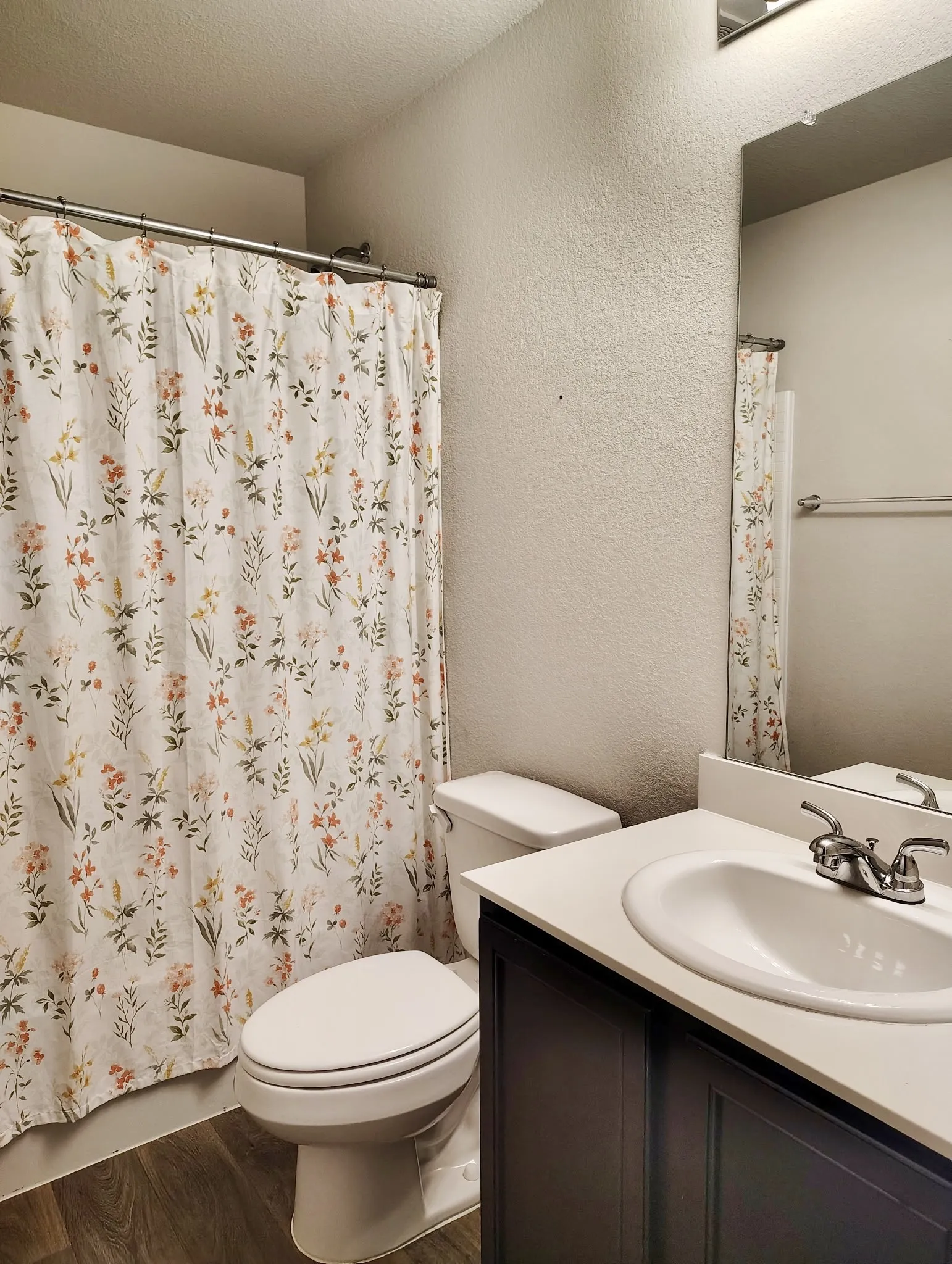 Bathroom featuring a white toilet, dark wood-finish vanity with an integrated white sink, chrome faucet, and a large wall-mounted mirror