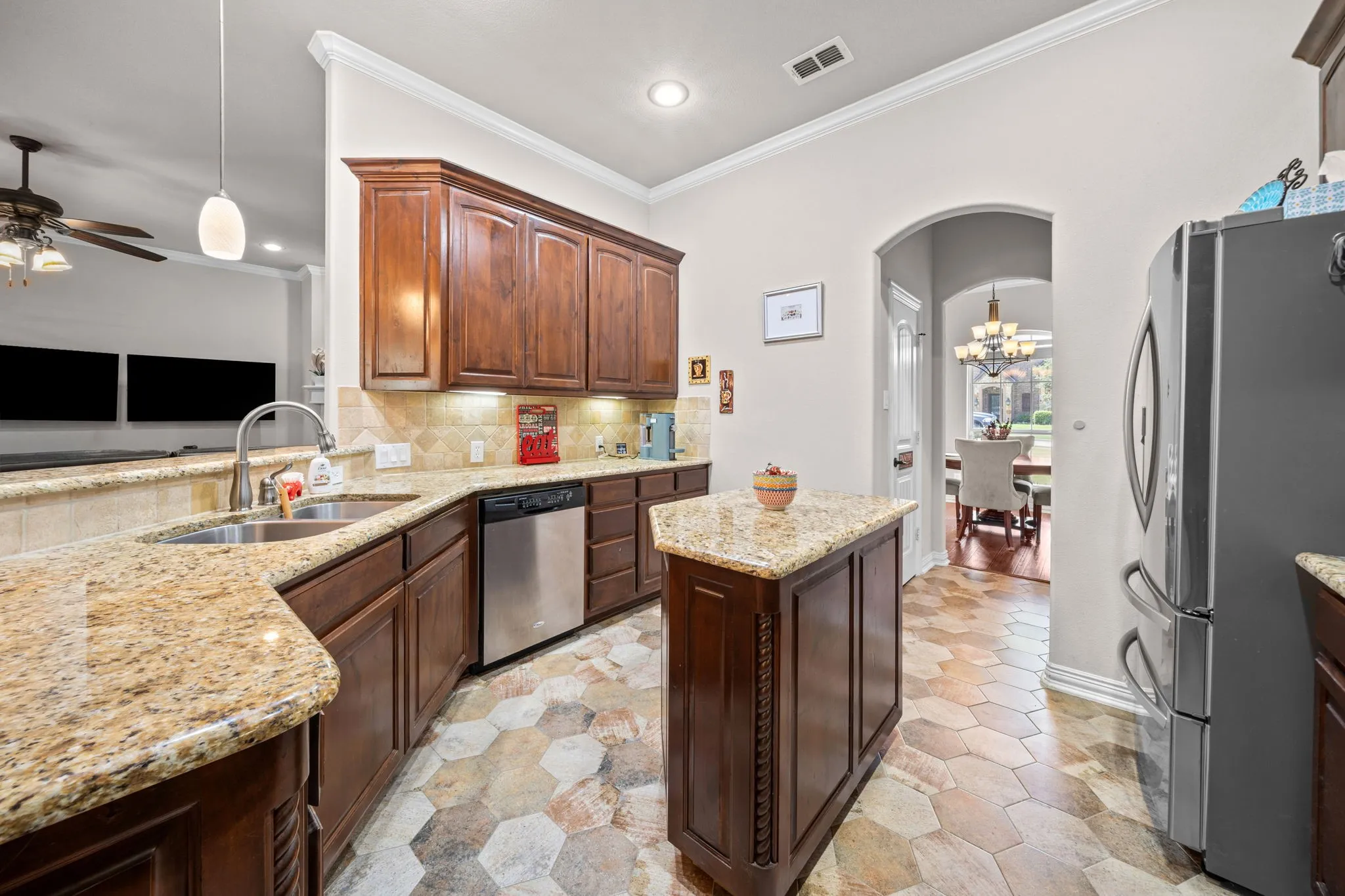 Another view of the kitchen featuring a double sink, granite island and stainless appliances.
