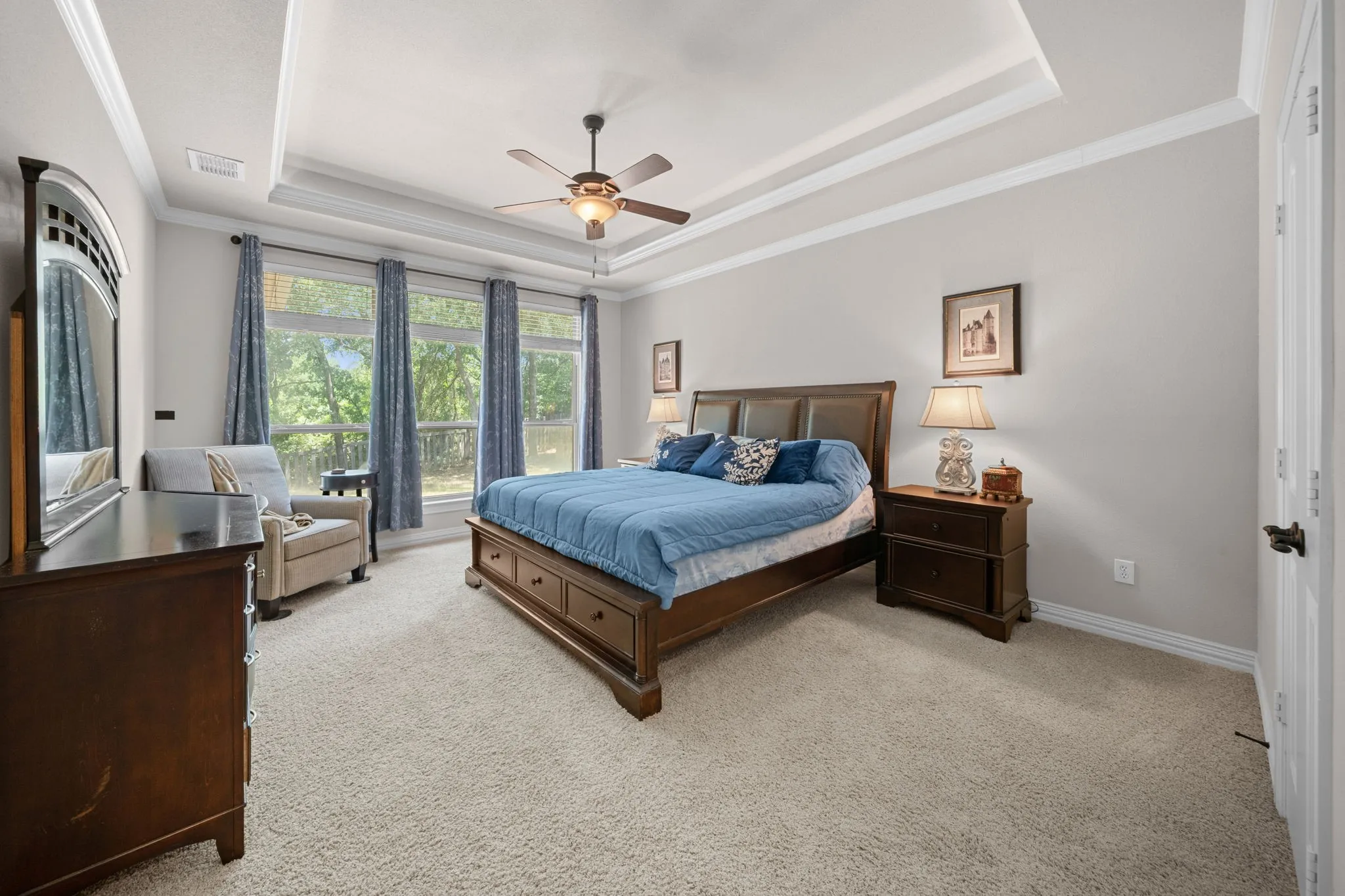 Primary bedroom with a wall of windows overlooking the serene backyard.