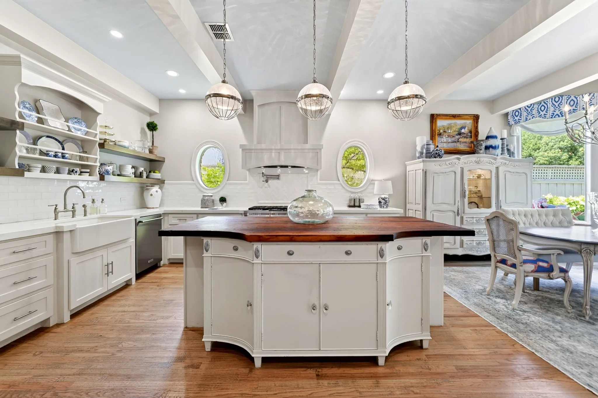 Kitchen featuring a custom island with a wood-finish countertop, white cabinetry, a farmhouse sink, and wood-finish flooring