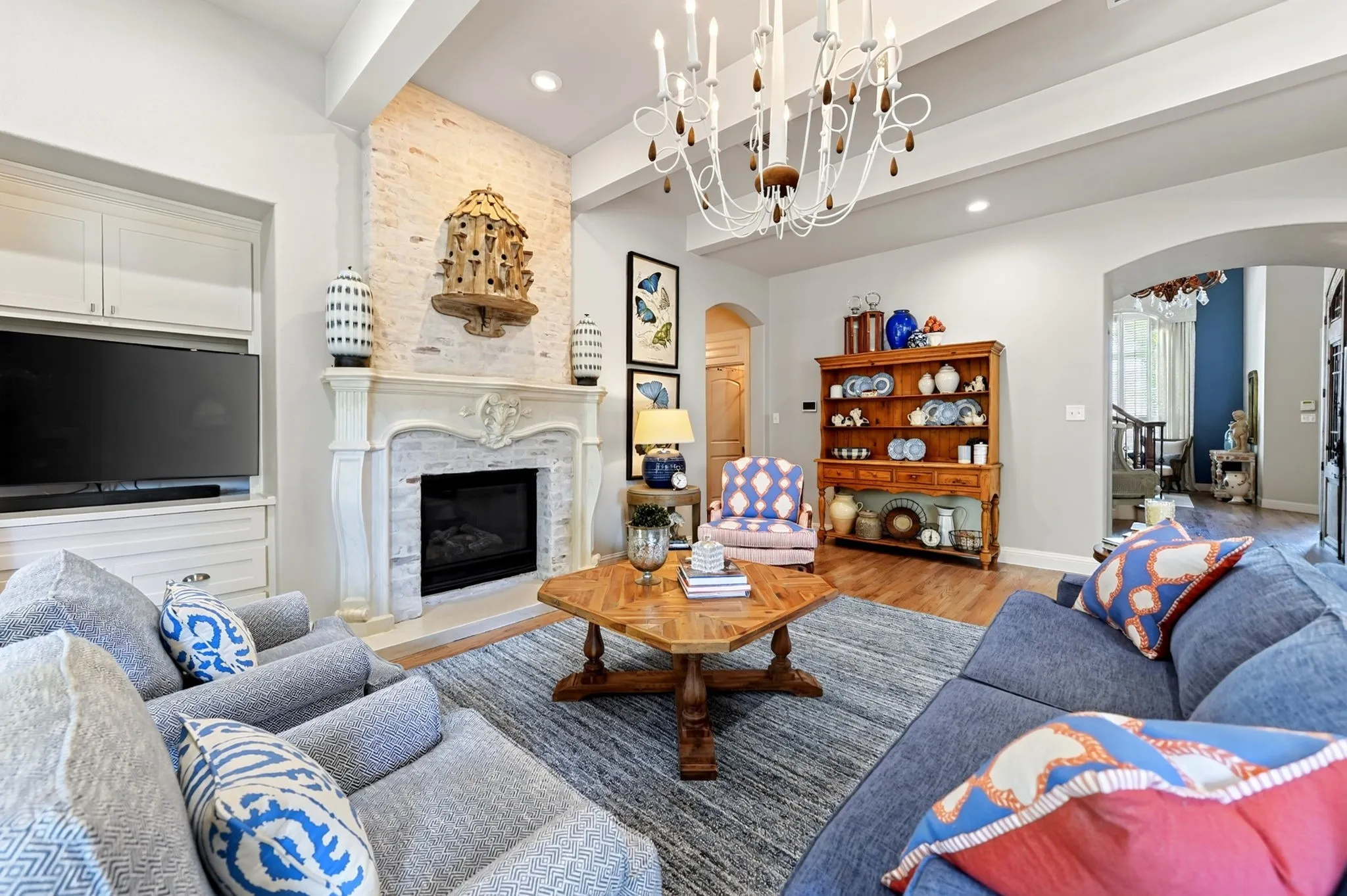 Living area featuring a detailed fireplace with a substantial mantel, built-in cabinetry, an exposed brick accent wall, a coffered ceiling, and a large area rug
