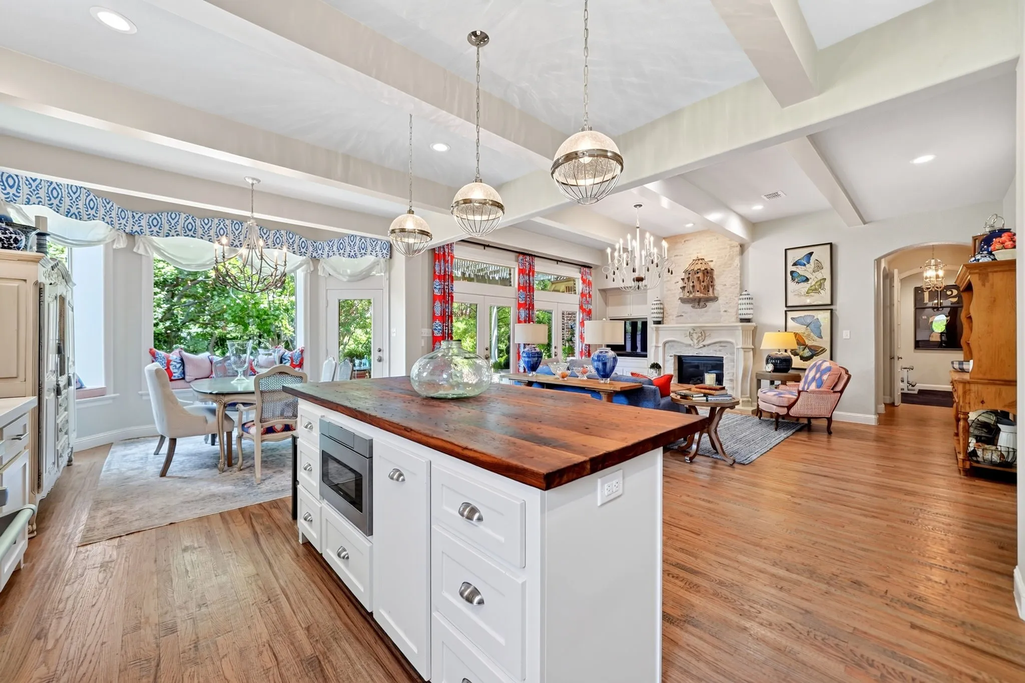 Open-concept living area featuring wood-finish flooring, exposed ceiling beams, and a central kitchen island with a wood countertop