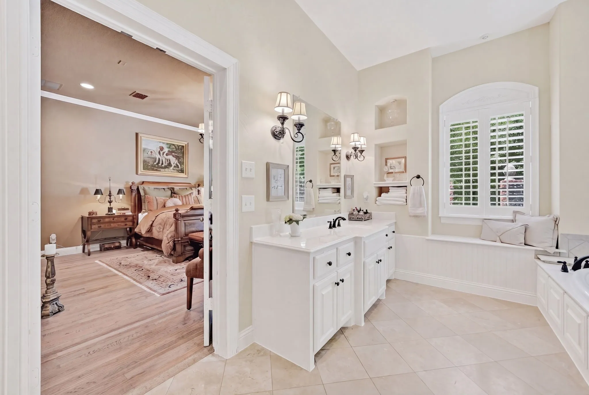 Bathroom featuring a double vanity with white cabinetry, wall-mounted sconces, and a deep soaking​​‌​​​​‌​​‌‌​‌‌​​​‌‌​‌​‌​‌​​​‌​​ tub
