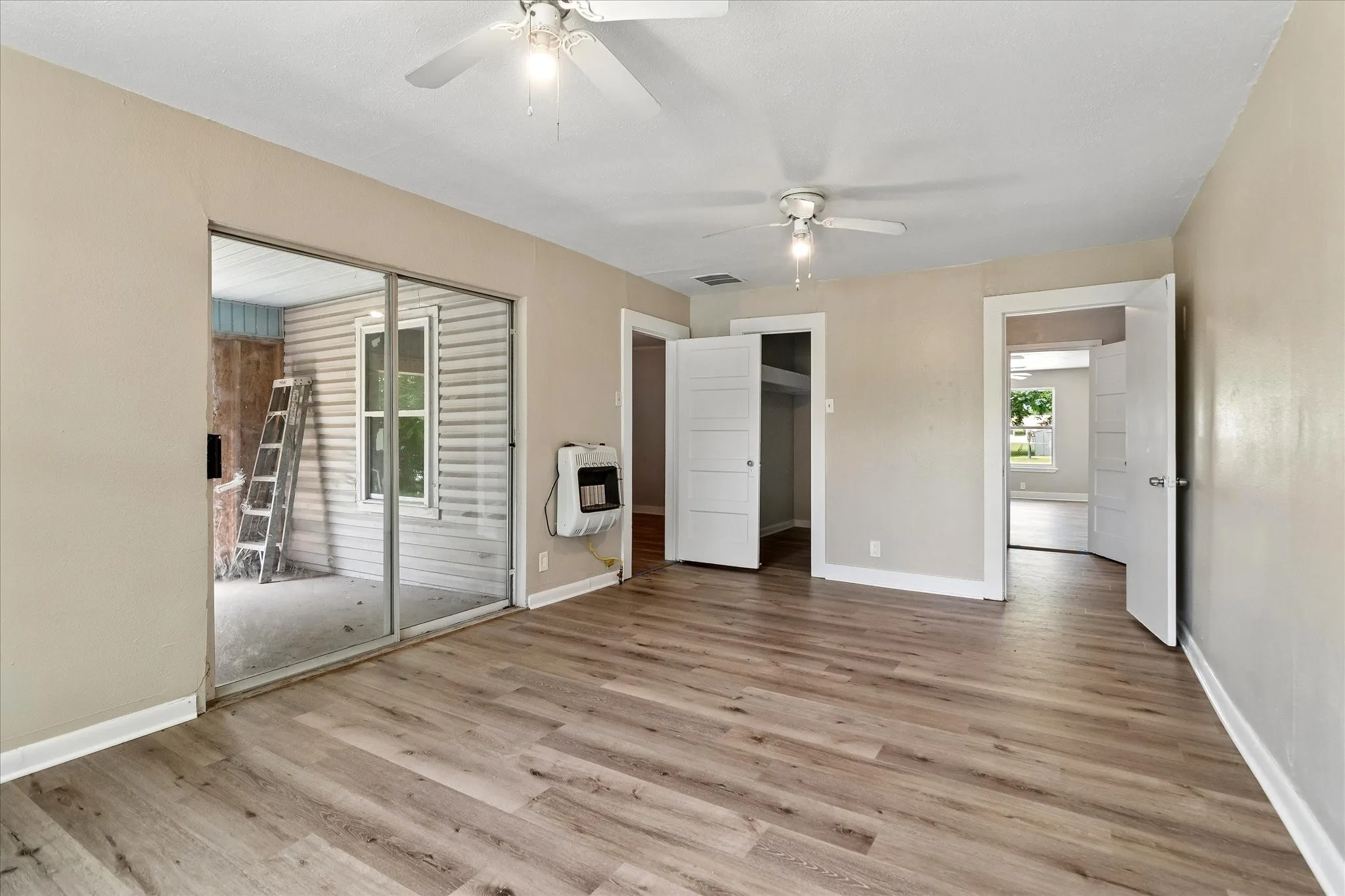 Primary bedroom with access to enclosed patio, door to the left is laundry room. Middle door is walk in closet. Door to the right is a closet that seperates primary to flex room.