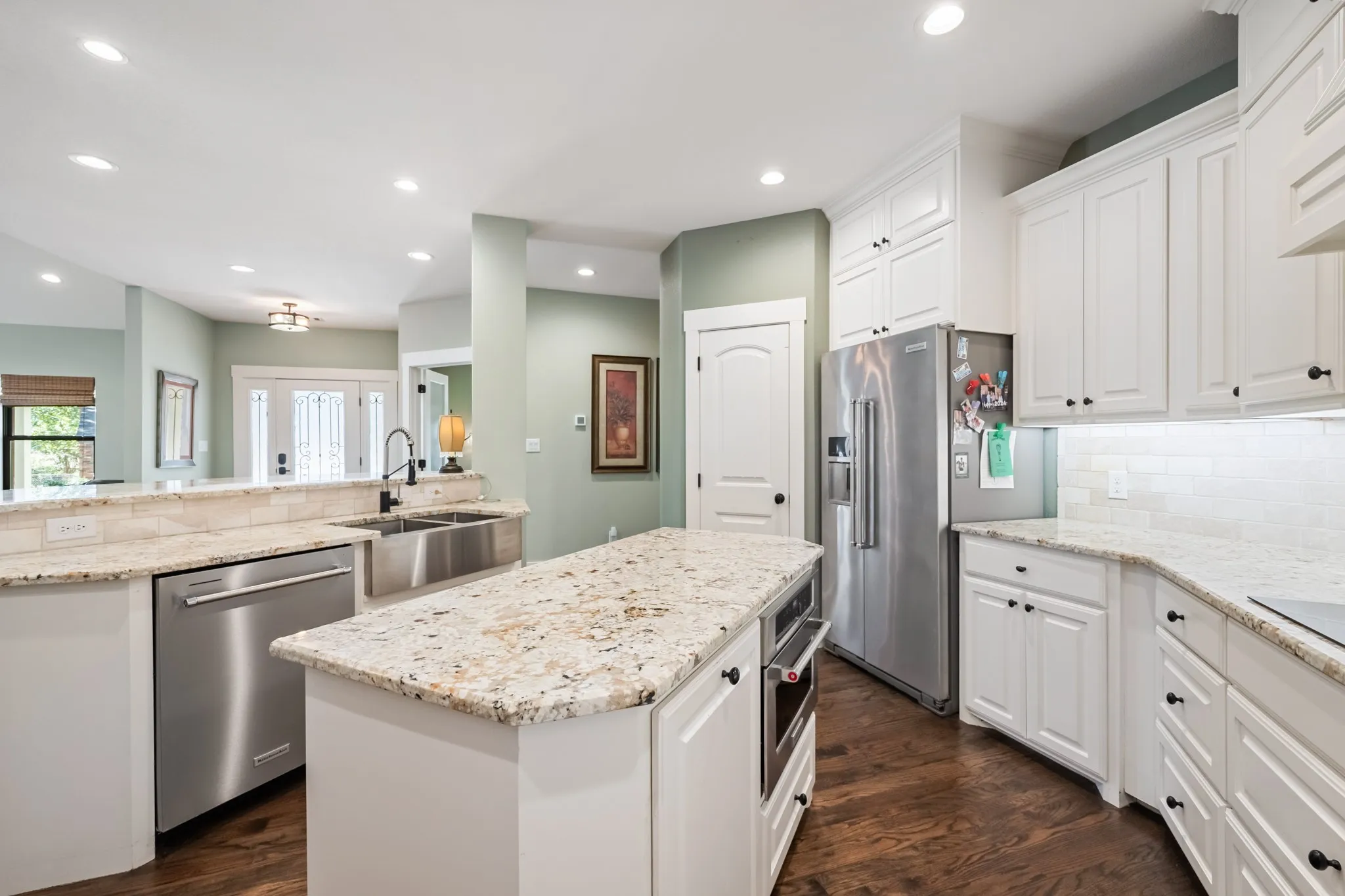 Kitchen featuring white cabinetry, light granite countertops, stainless steel appliances, and a farmhouse sink