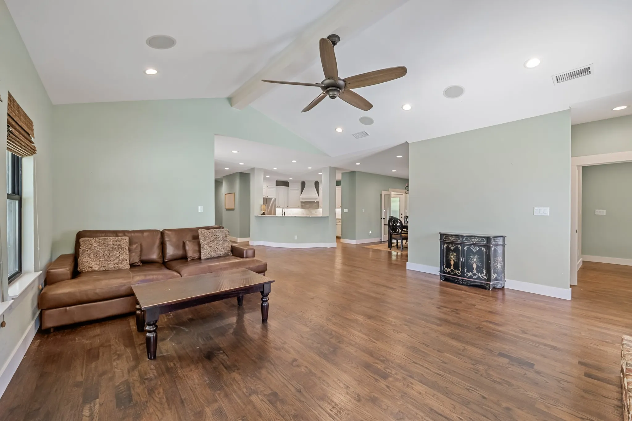 Vaulted ceiling with exposed beam, recessed lighting, wood-finish flooring, ceiling fan, and built-in ceiling speakers