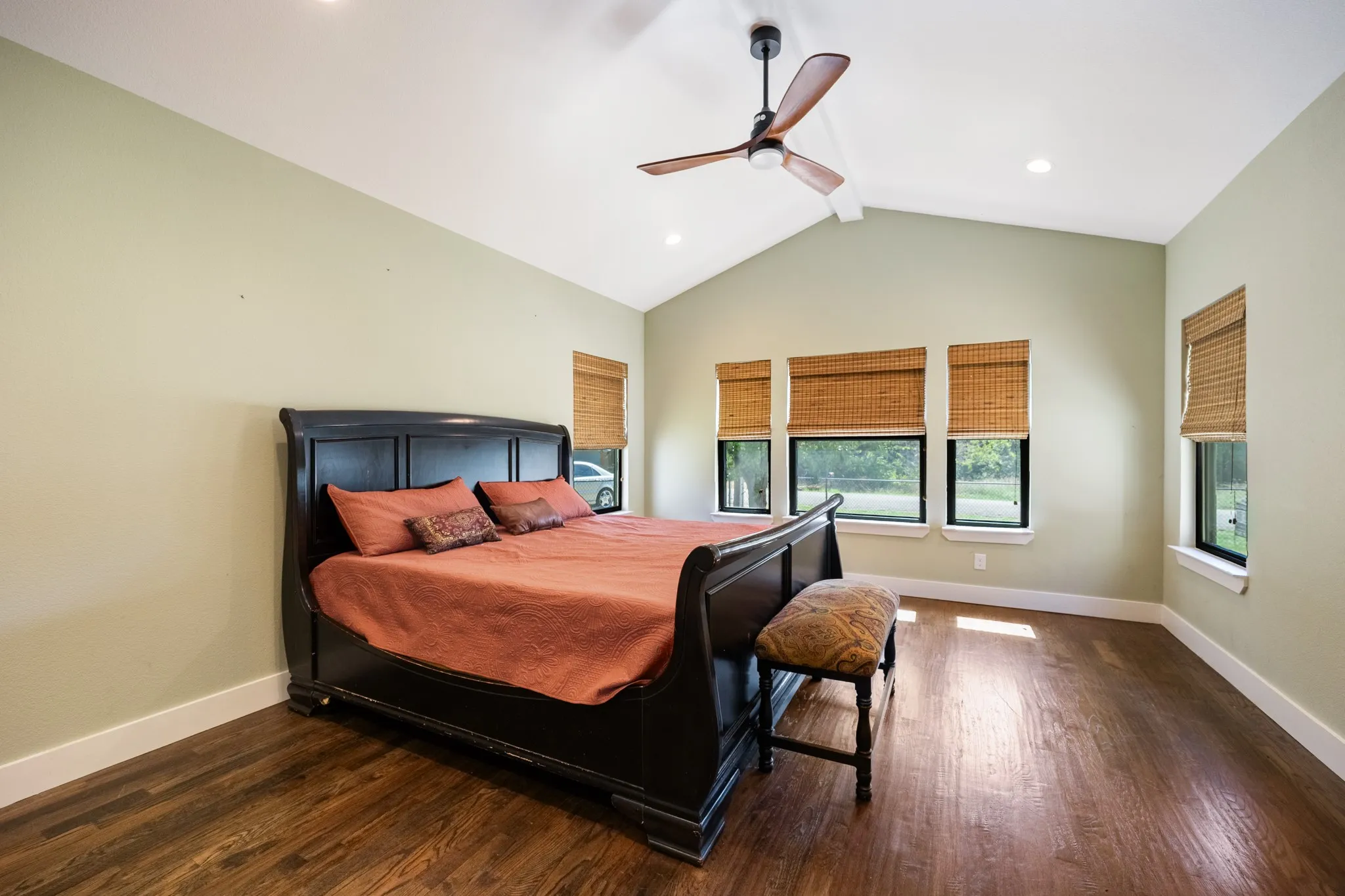 Vaulted ceiling with a ceiling fan, recessed lighting, wood-finish flooring, and multiple windows