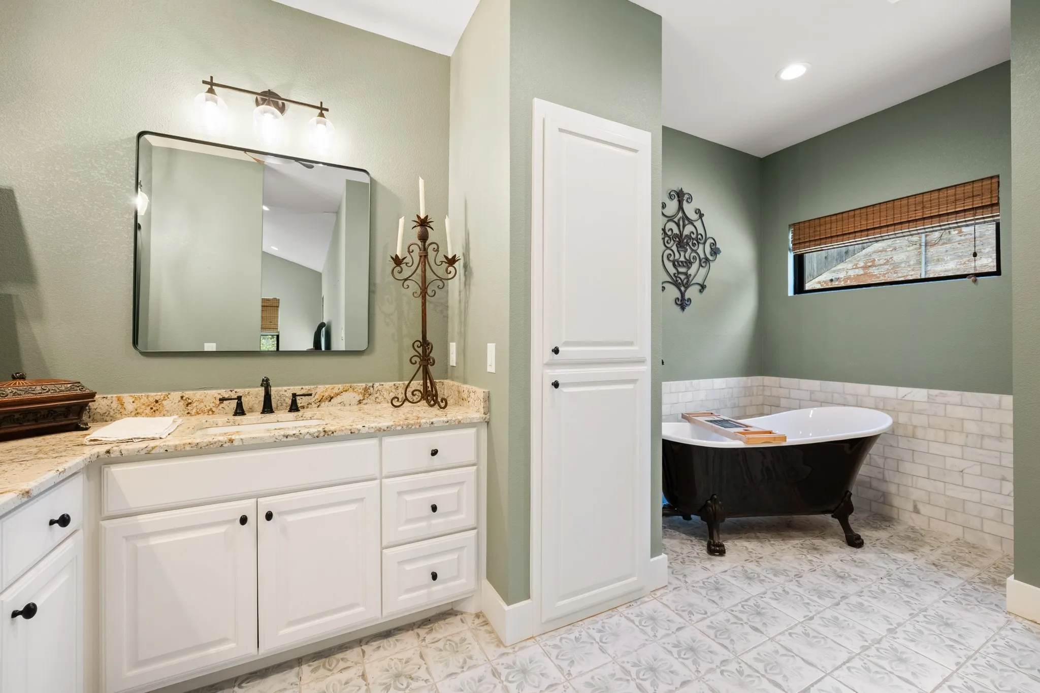 White vanity with a light-toned countertop, rectangular mirror, and three-light fixture