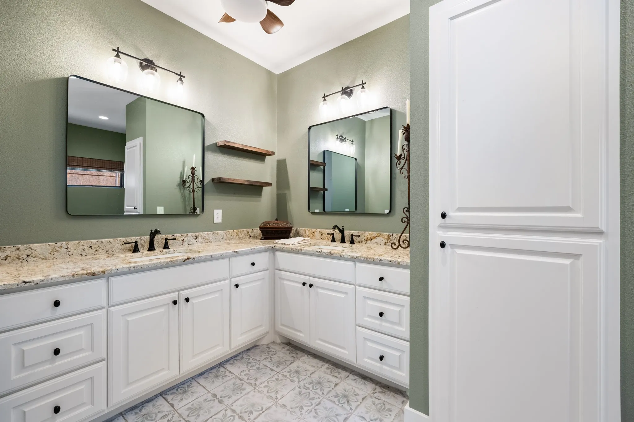 Dual vanity with light-toned countertop, white cabinetry with black hardware, and two framed mirrors
