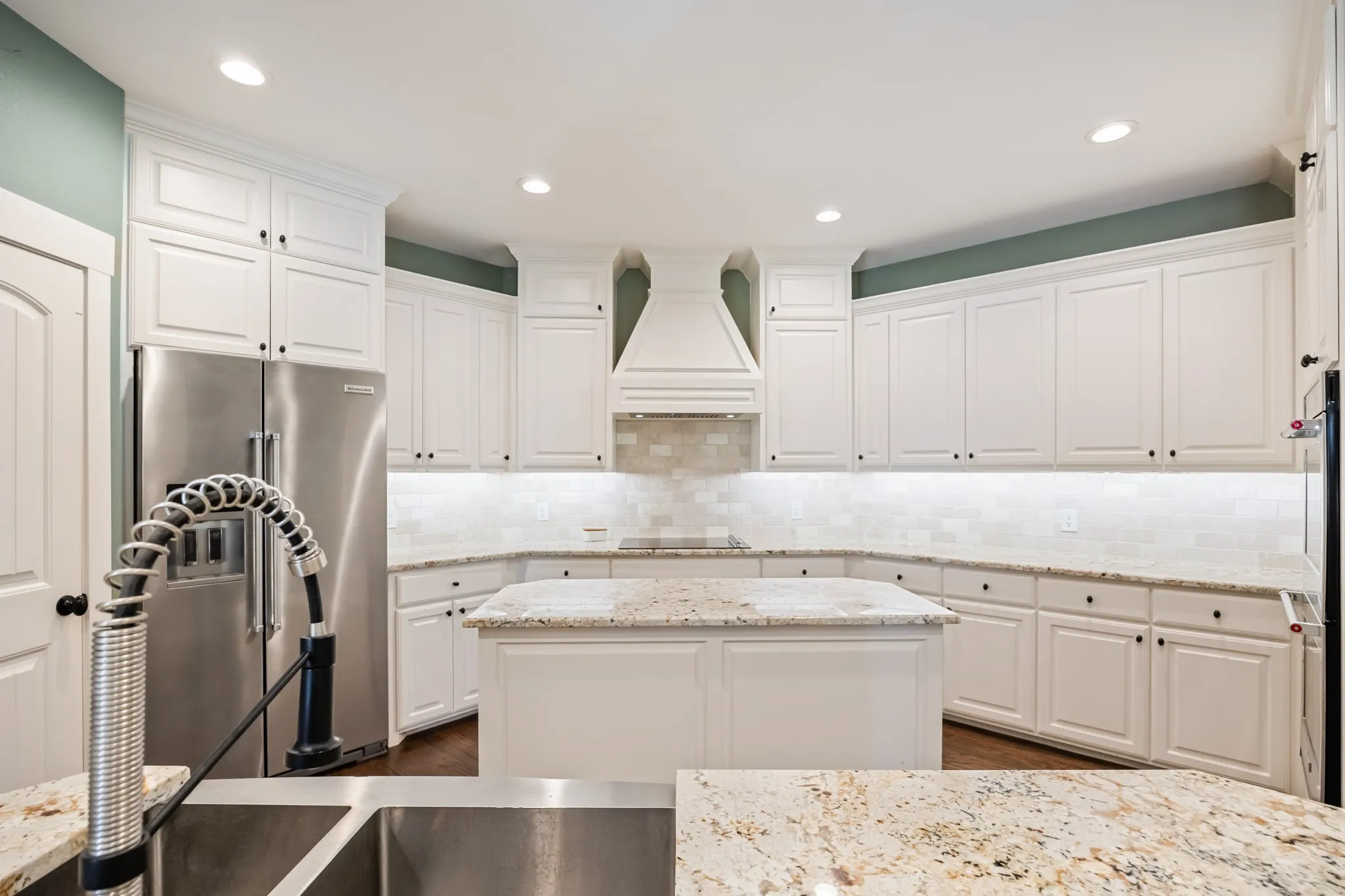 Kitchen with white cabinetry, stainless steel appliances, granite countertops, and a center island