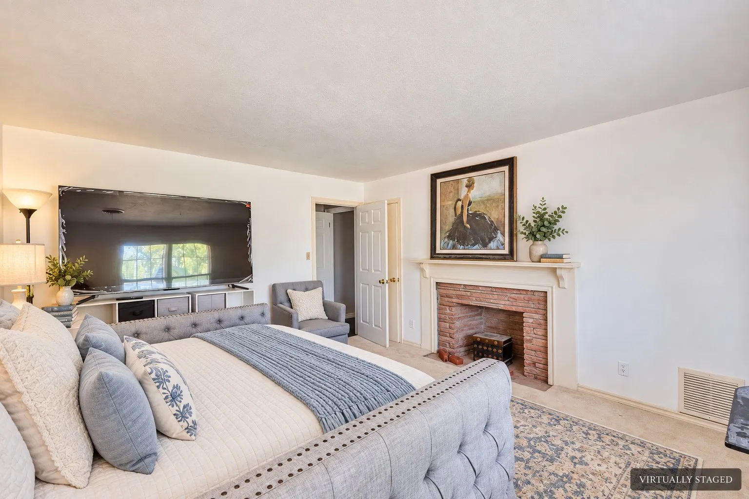 Spacious room with a brick-faced fireplace, white mantel, and light-colored carpeting
