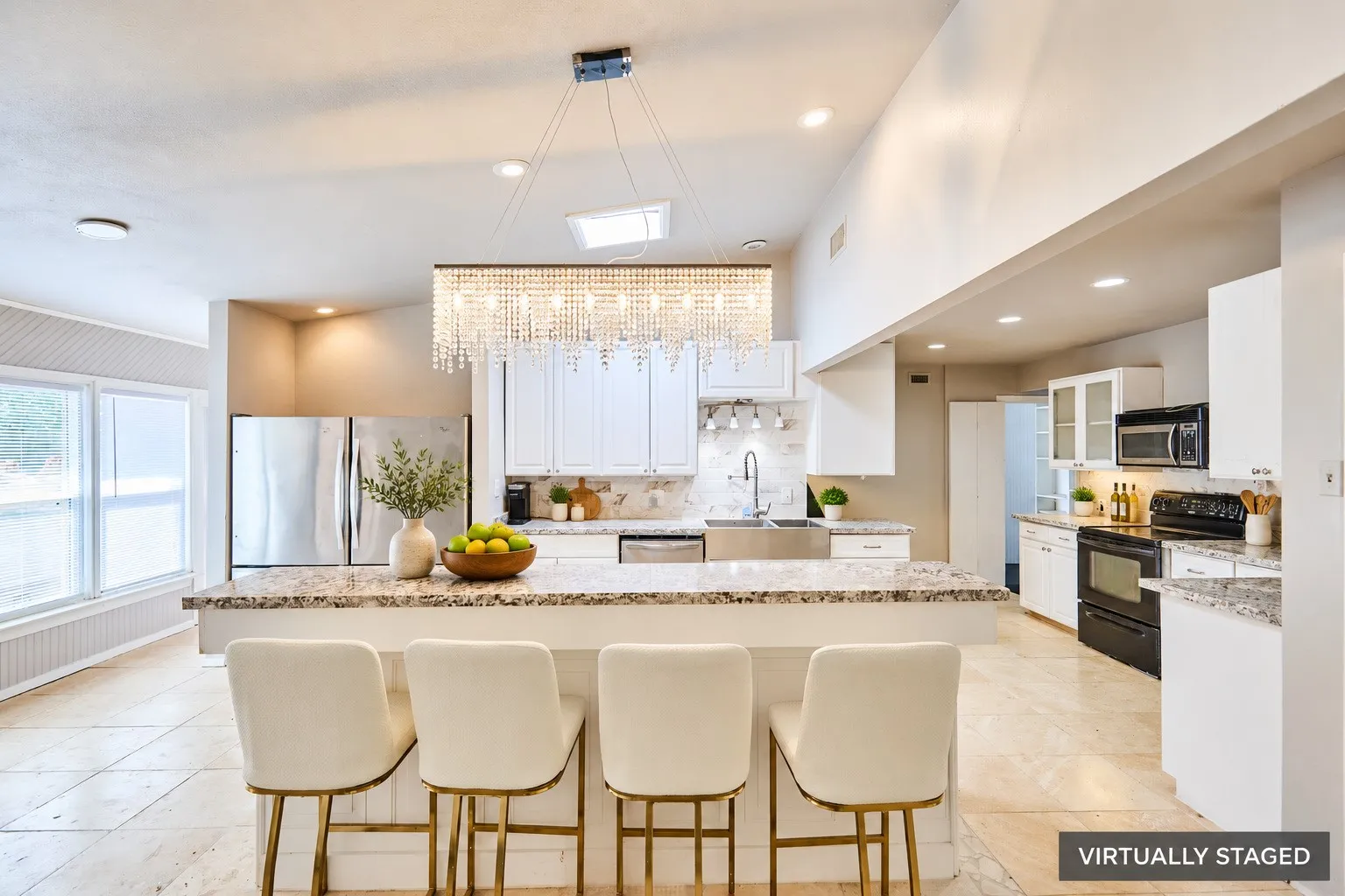 Spacious kitchen featuring an expansive island, stainless steel refrigerator, white cabinetry, integrated sink, and recessed lighting