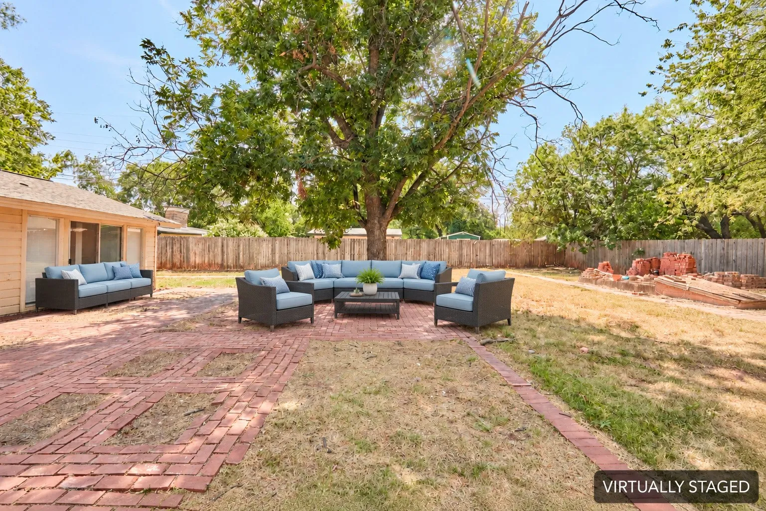Expansive backyard featuring a brick patio, mature trees, and a perimeter fence