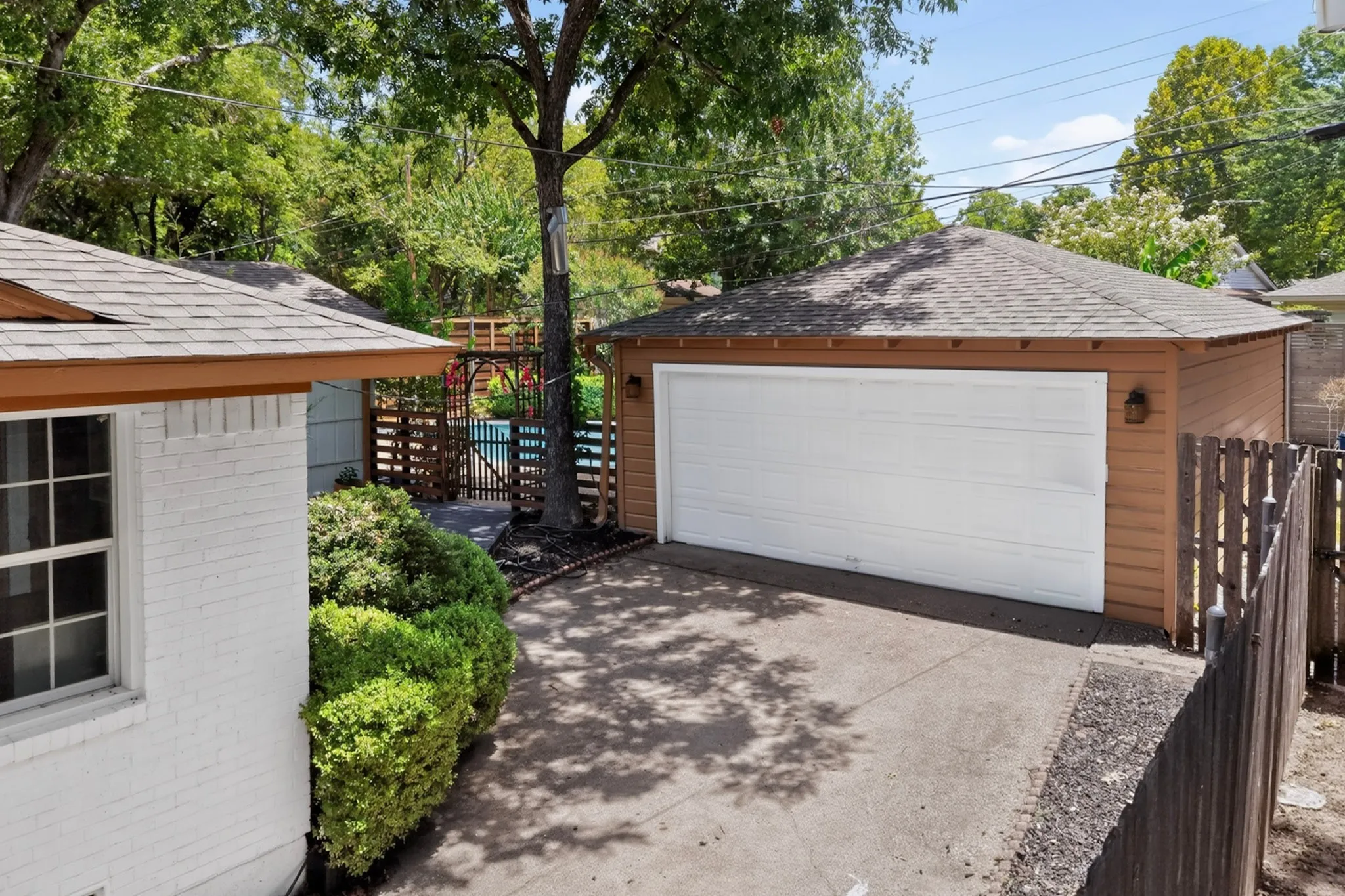 Detached garage featuring a white overhead door and tan siding