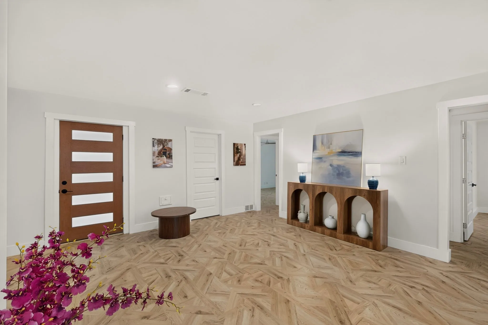 Entryway featuring a modern wood-finish door with frosted glass panels, light wood-finish flooring with a geometric pattern, neutral wall finishes, white trim, and recessed lighting