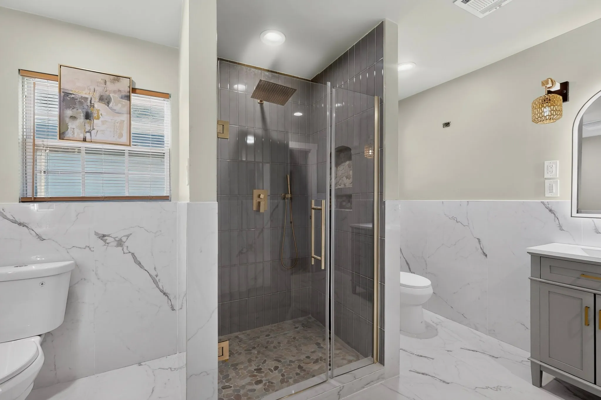 Glass-enclosed shower with a rain shower head and pebble-tiled floor