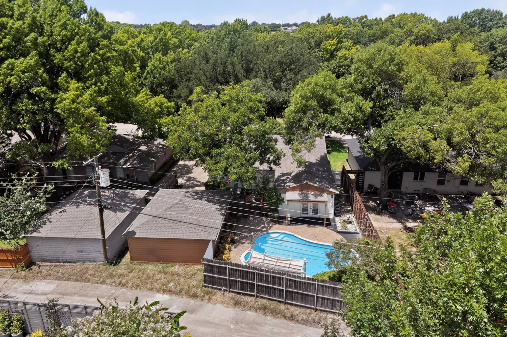 Rear exterior with a fenced in-ground pool, surrounded by mature trees